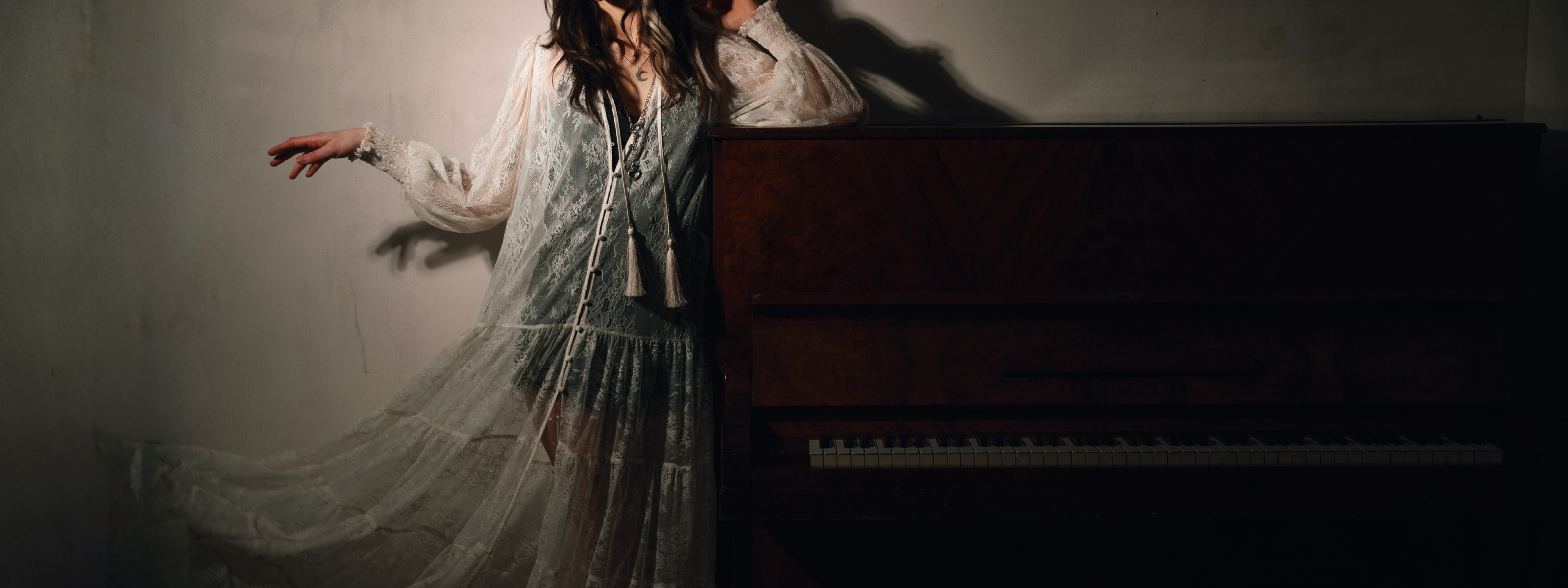 Sheer Rhiannon Ivory Maxi Dress
from Little Lies’ spring collection styled beside a vintage upright piano in soft moody lighting.