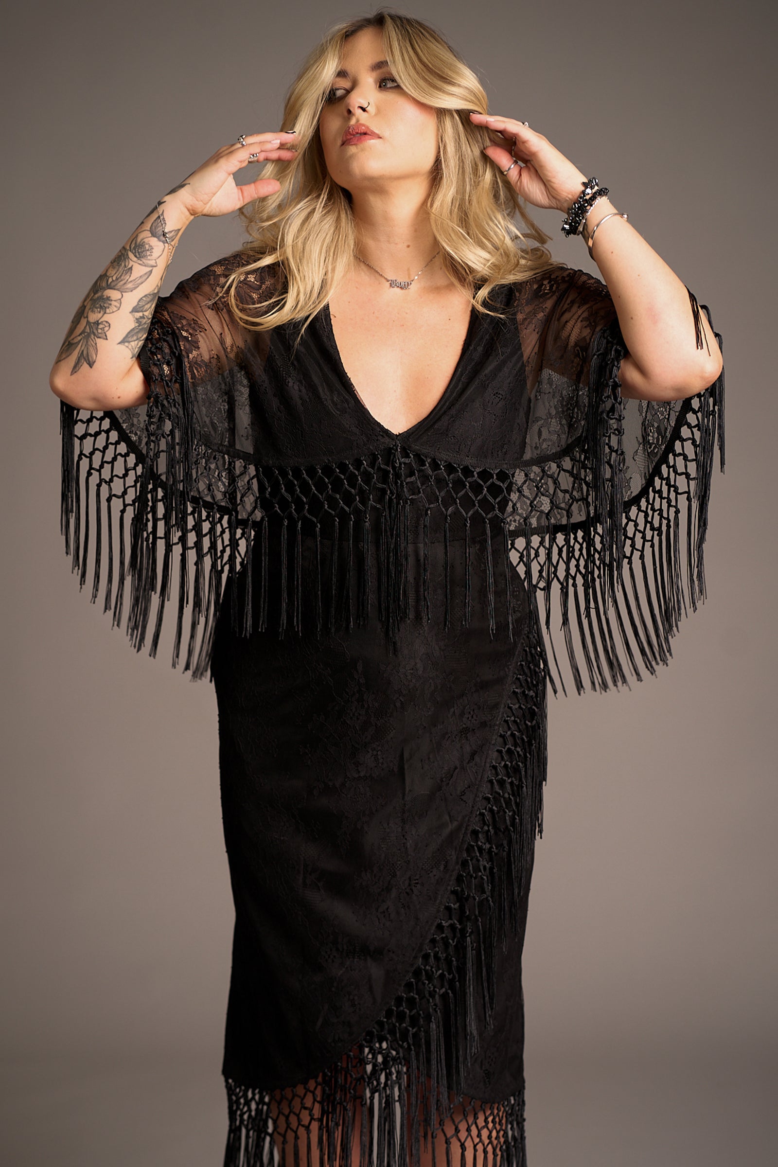 Erin showcasing the cape and fringe details on the Tango in the Night Lace Midi Dress