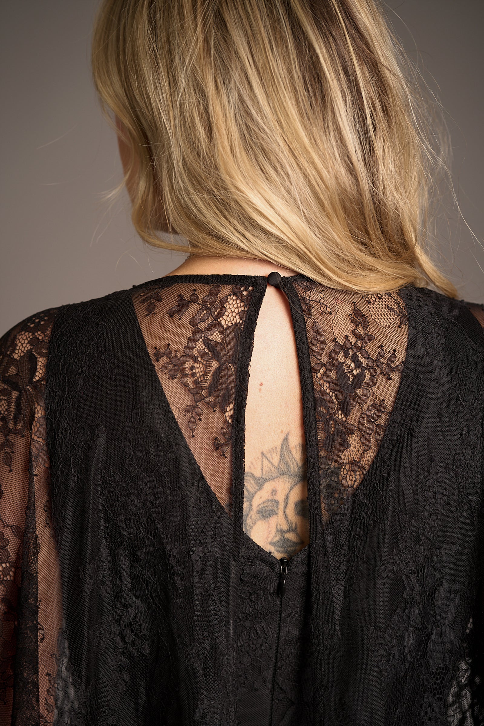 Erin showcasing the button and zip closure details on the Tango in the Night cape lace midi dress