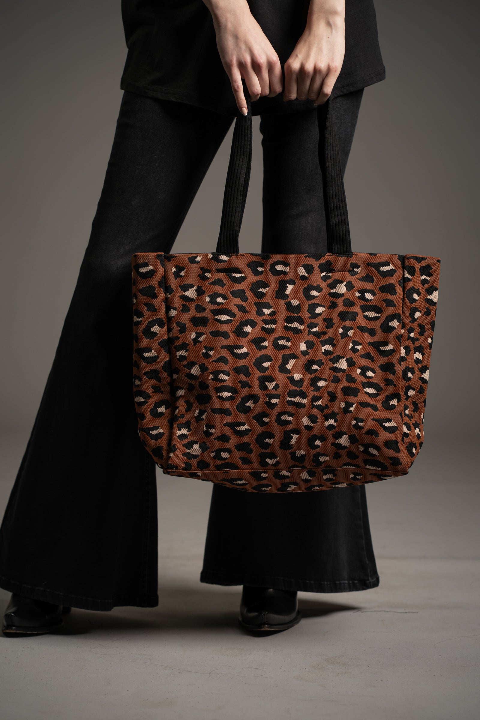 Model holding Wild Nights Leopard Shopper bag with black handles by Little Lies photographed in studio on neutral background