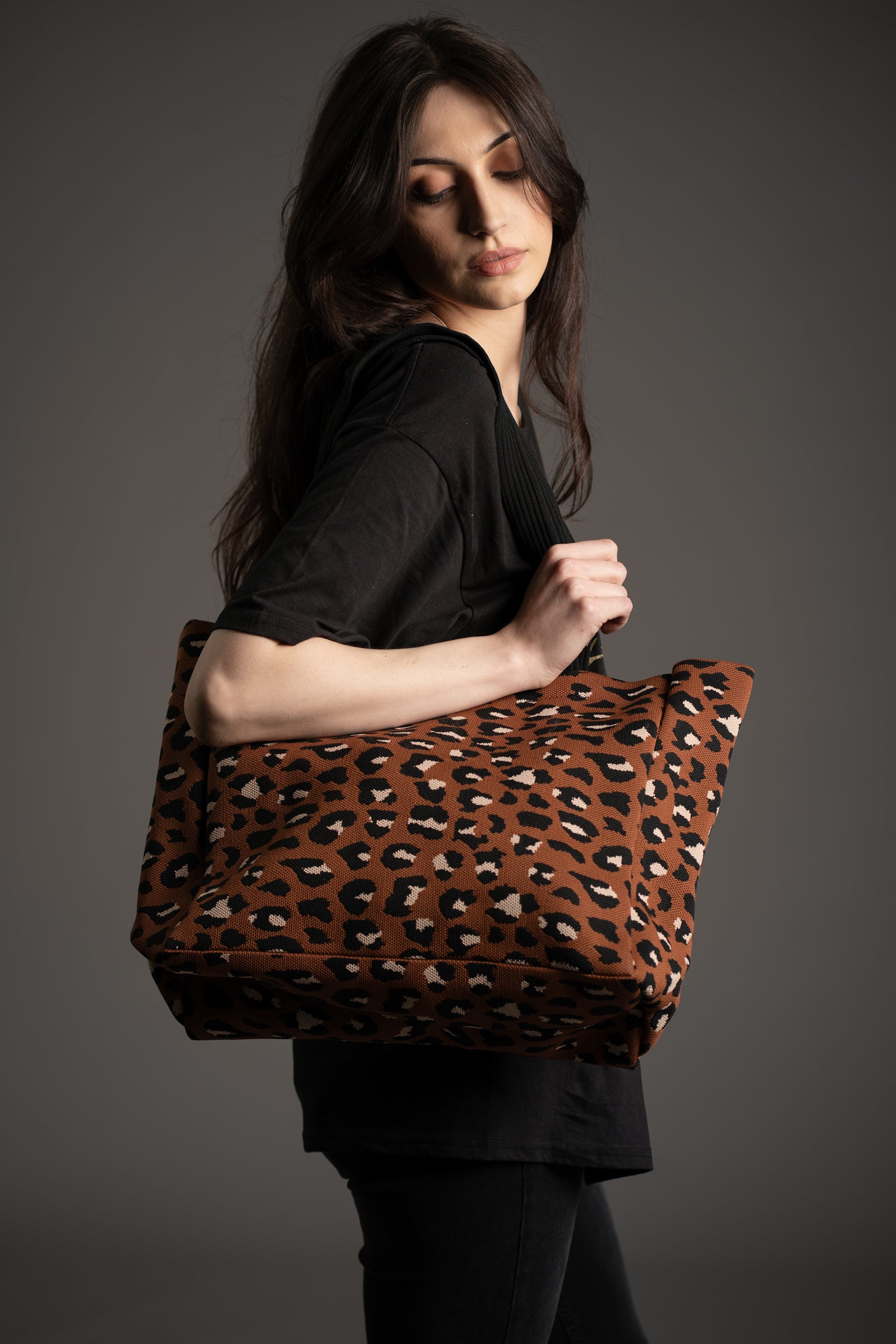 Model Andie carrying Wild Nights Leopard Shopper tote bag in brown and black animal print by Little Lies in studio setting