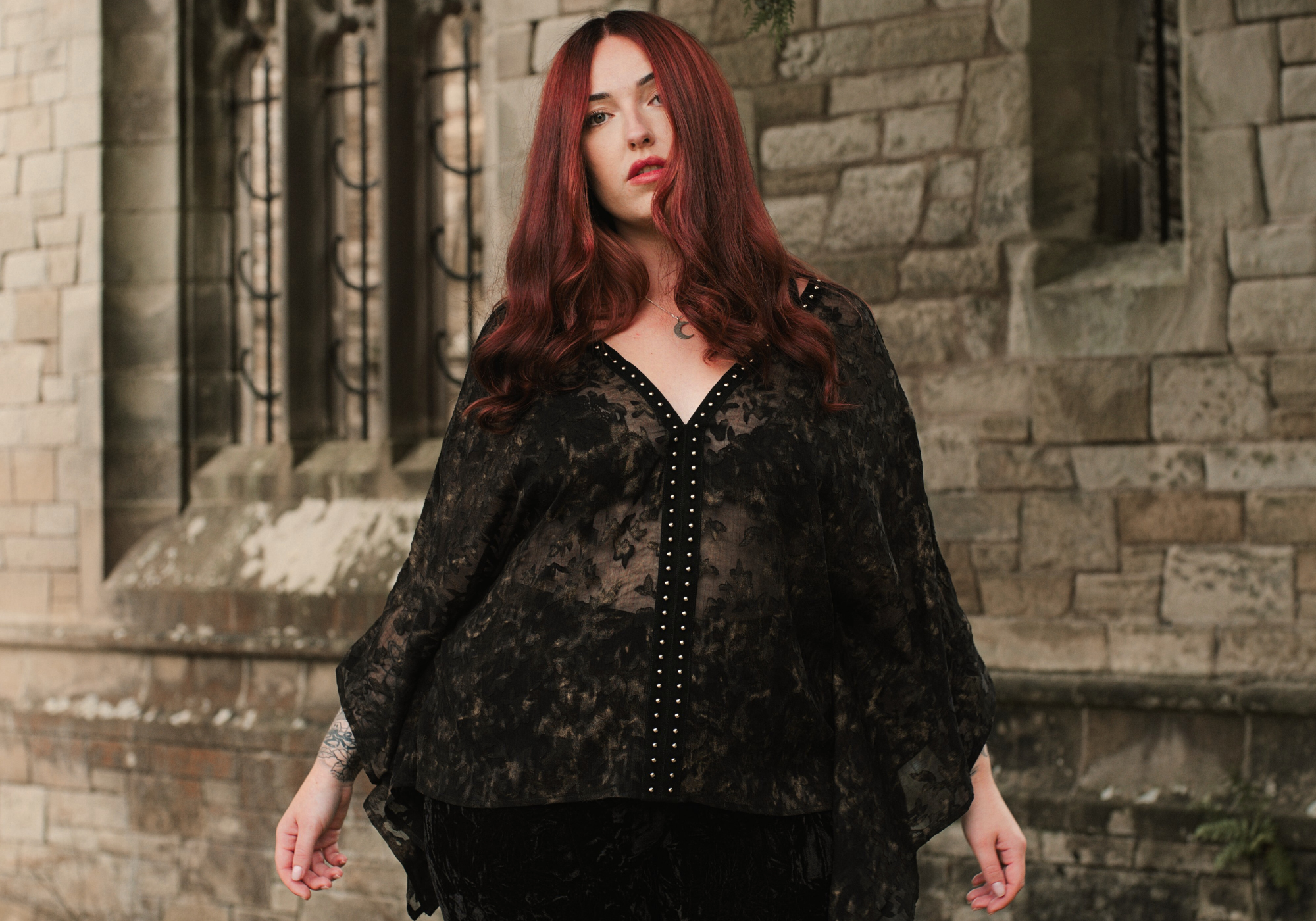 Taylor models Little Lies Bella Donna studded kimono top in black devore fabric – styled in outdoor stone architecture setting