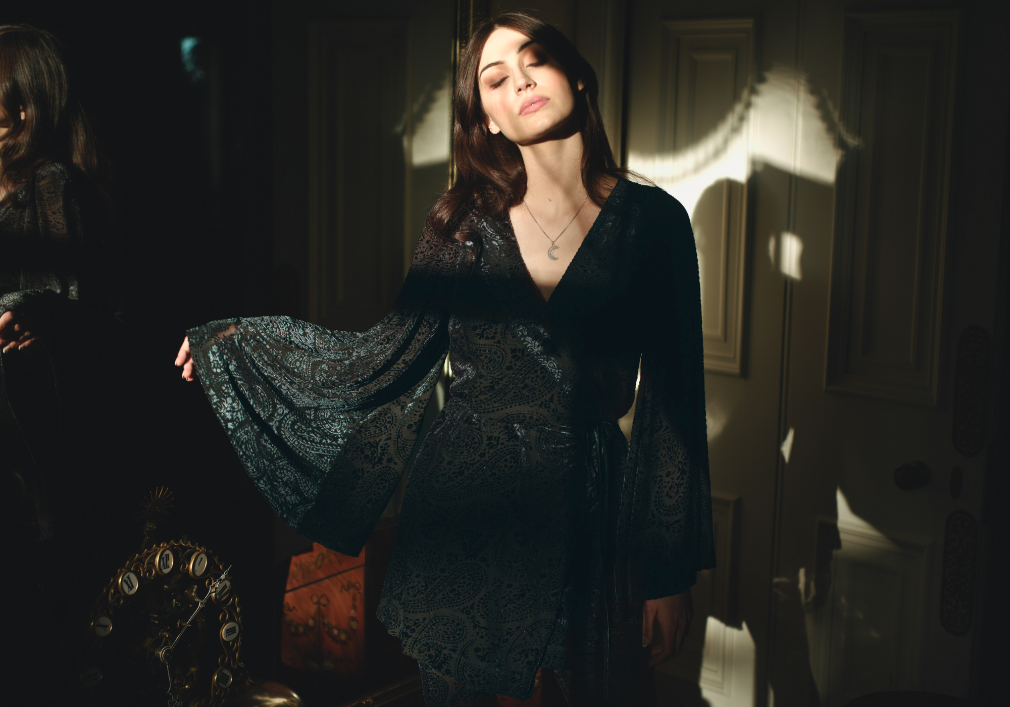 Andie models Little Lies Siren Teal Devore Wrap Dress featuring rich teal velvet devore fabric with sheer sleeves, wrap silhouette, and tie waist detail styled in an elegant indoor setting