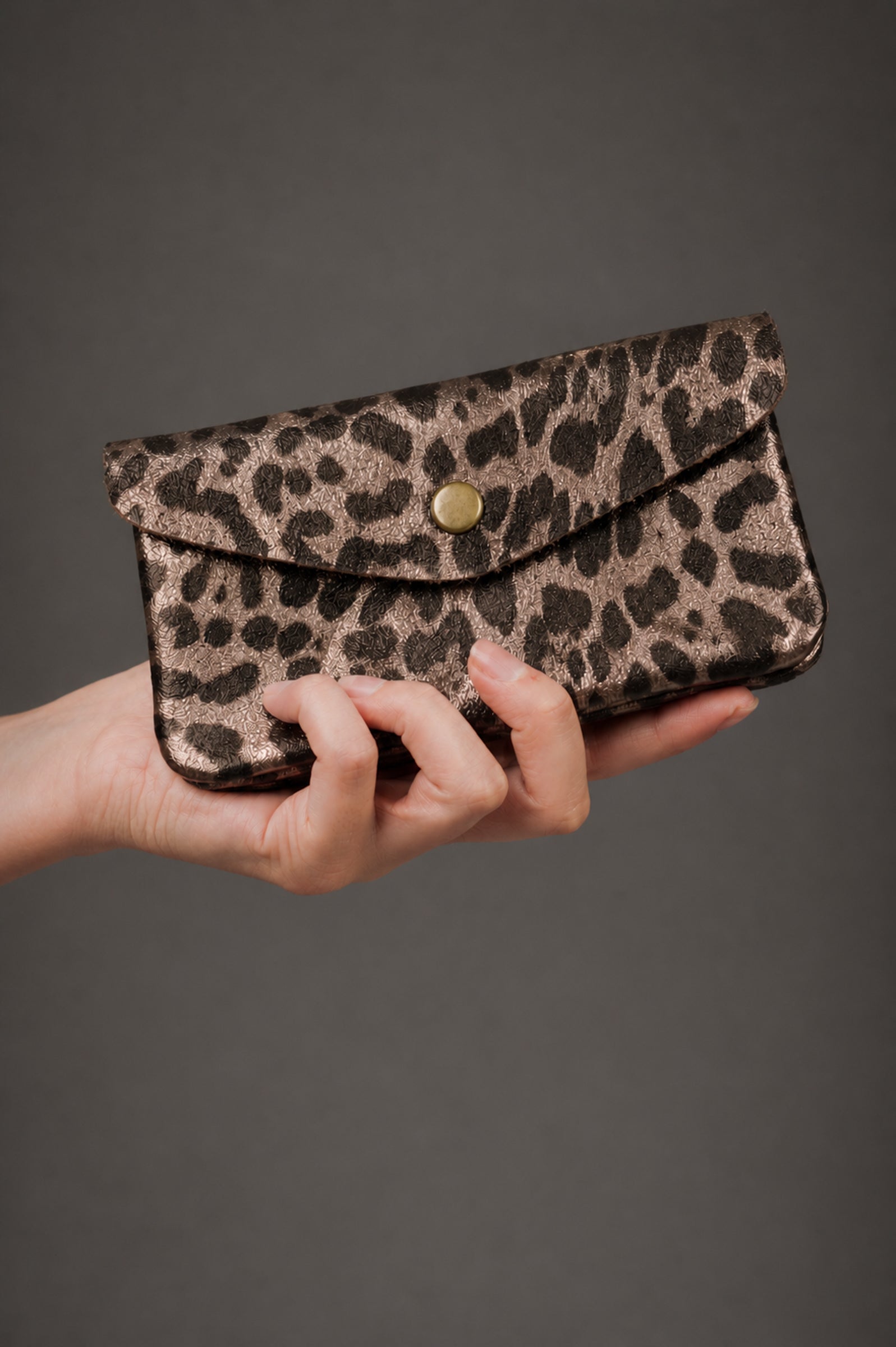 Bronze metallic genuine suede purse with leopard print pattern held in a hand.