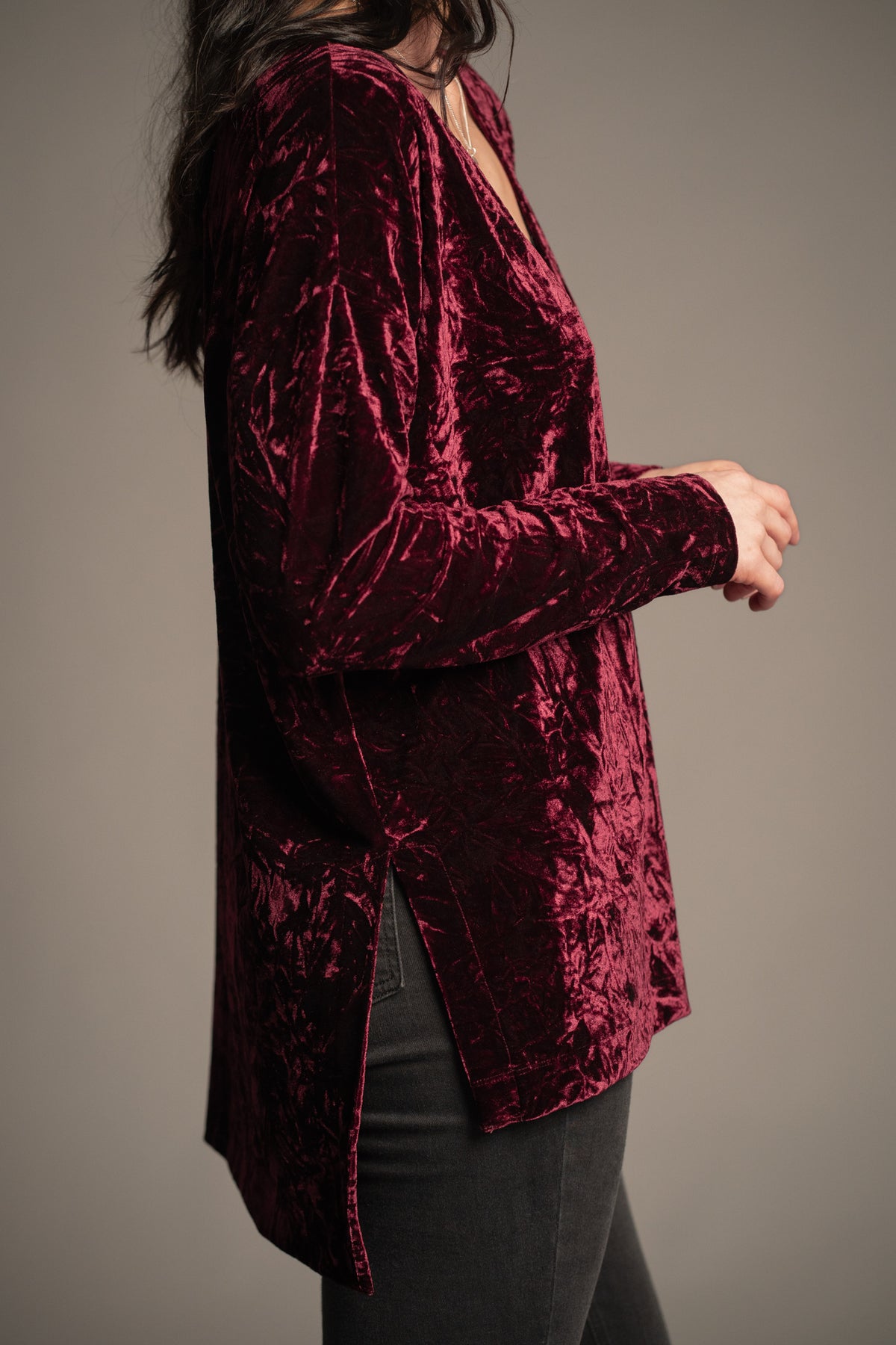 Side view of Dylan Merlot crushed velvet tee in merlot red featuring long sleeves, side split hem and draped relaxed fit