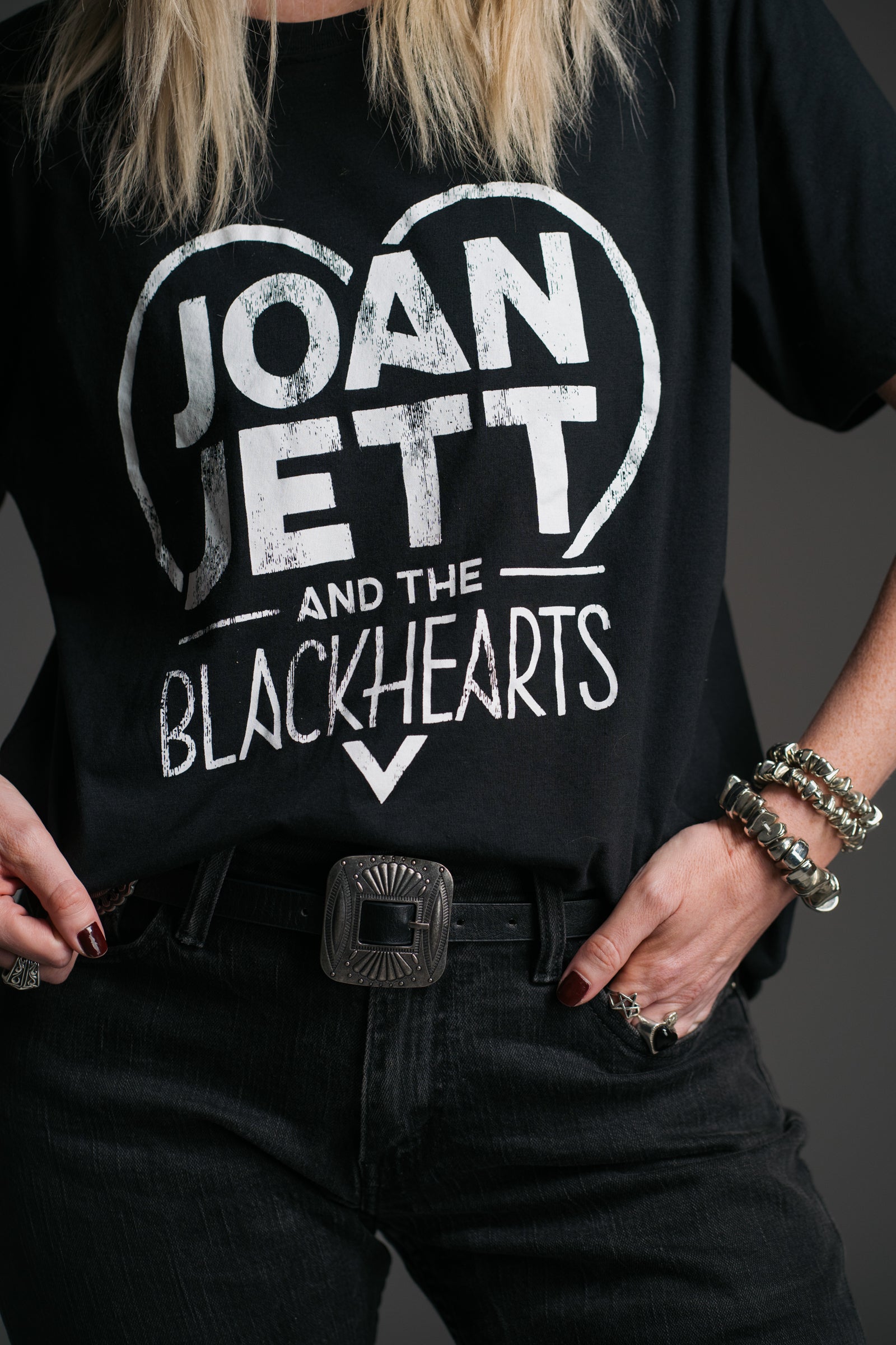 Sara wears unisex black Joan Jett and the Blackhearts vintage‑style band t‑shirt by Little Lies, styled with western belt and silver jewellery
