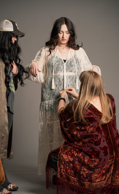 Behind-the-Scenes Image, Little Lies Rhiannon ivory maxi dress with delicate lace detailing, tassel tie neckline and flowing sheer layers in relaxed boho silhouette
