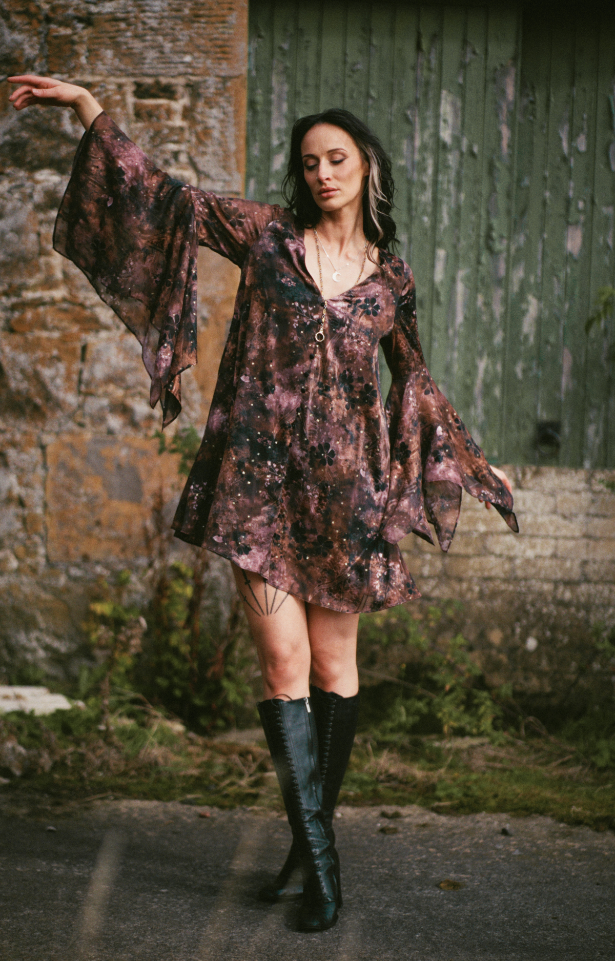 Little Lies Practical Magic mini dress in a burgundy celestial print with flared bell sleeves and knee-high boots.