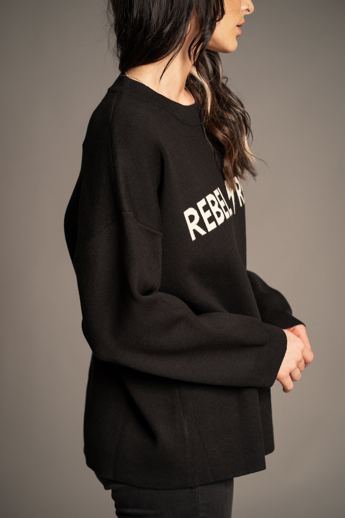 Side view of Rebel Rebel Knit Jumper in black with dropped shoulders and relaxed oversized fit