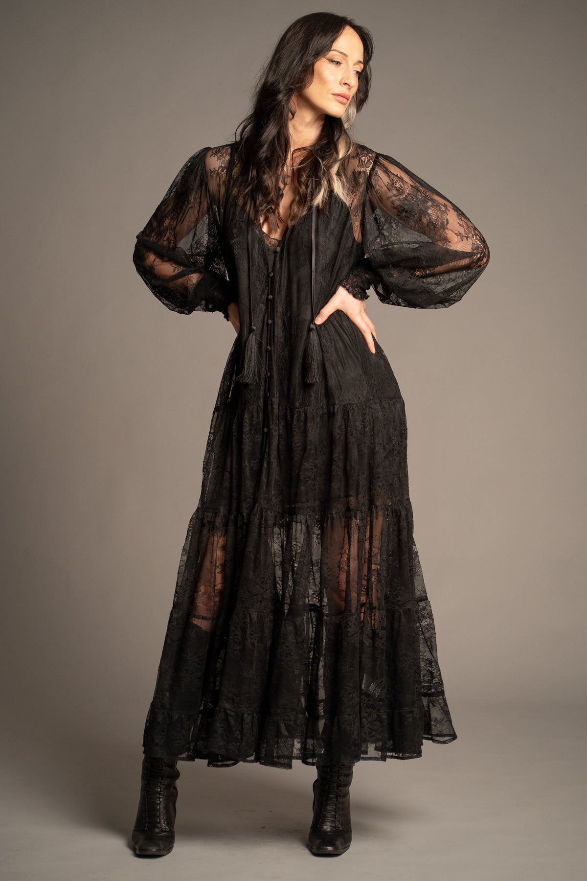 Rhiannon black lace maxi dress with tiered skirt, sheer lace sleeves and tassel tie neckline front view