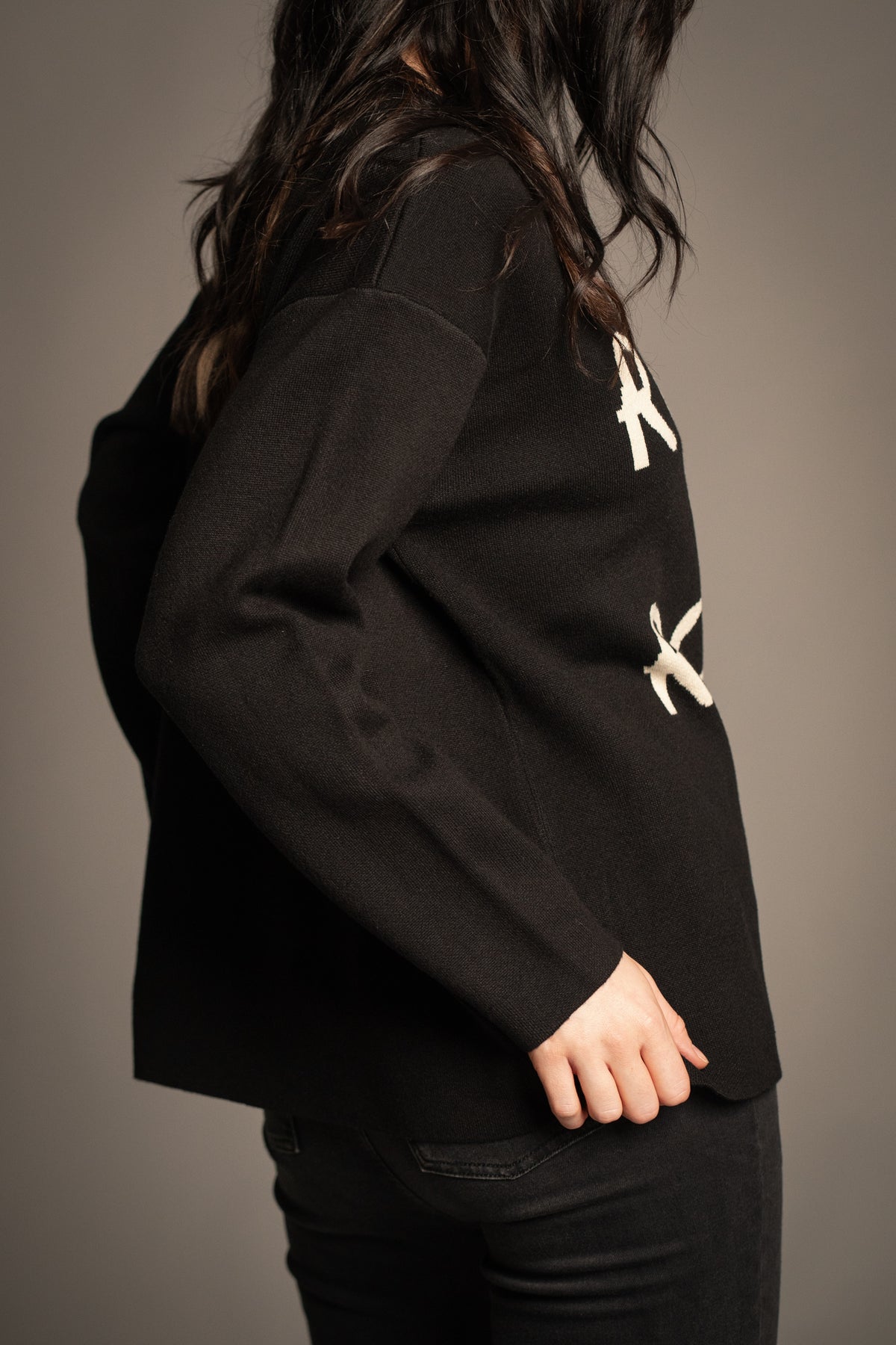 Side view of the Little Lies Rock & Roll Knit Jumper in black with a relaxed silhouette, drop shoulders and long sleeves
