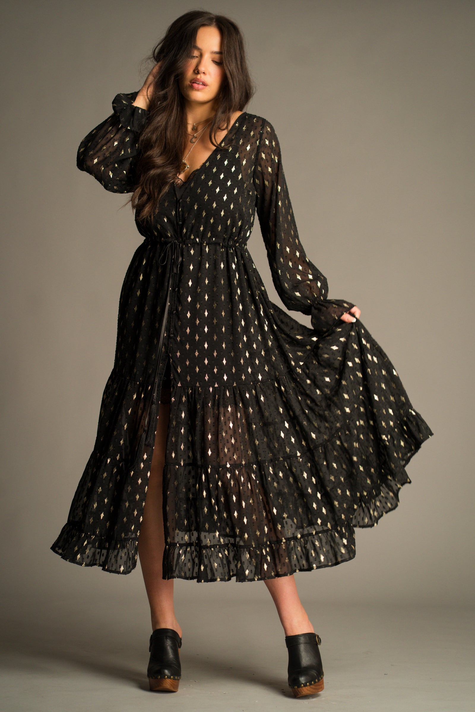 Front view of the Space Oddity Metallic Maxi Dress featuring a sheer black overlay, metallic gold foil print, drawstring waist and tiered maxi silhouette