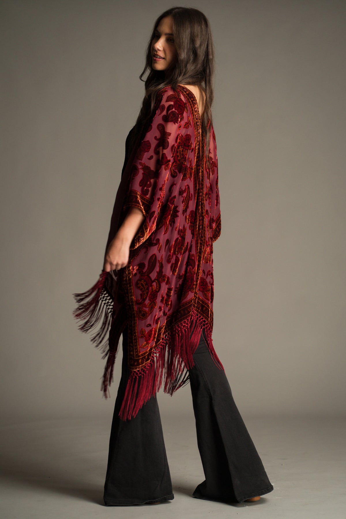 Side view of the Stevie Plum Paisley Devore Kimono showcasing sheer devore velvet fabric, intricate paisley detailing and dramatic fringe movement