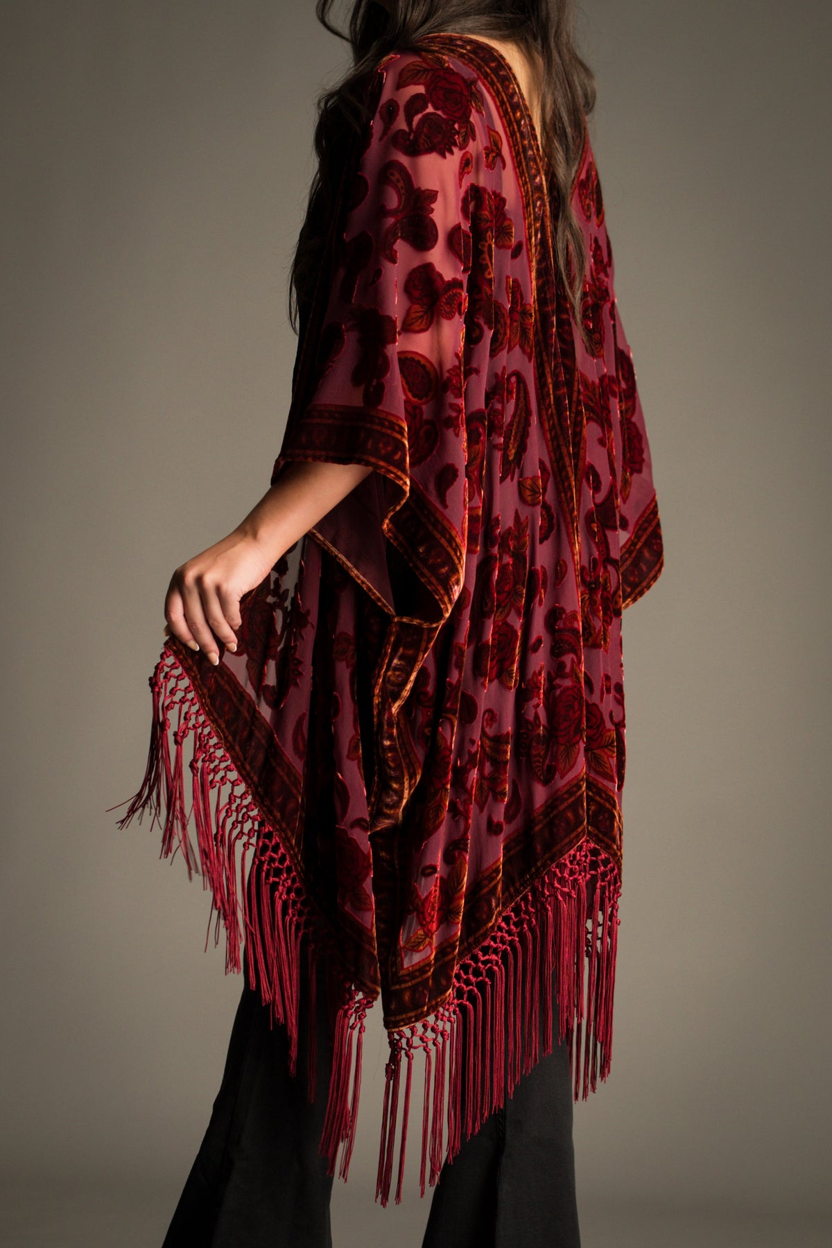 Side view of the Stevie Plum Paisley Devore Kimono showcasing sheer devore velvet fabric, intricate paisley detailing and dramatic fringe movement