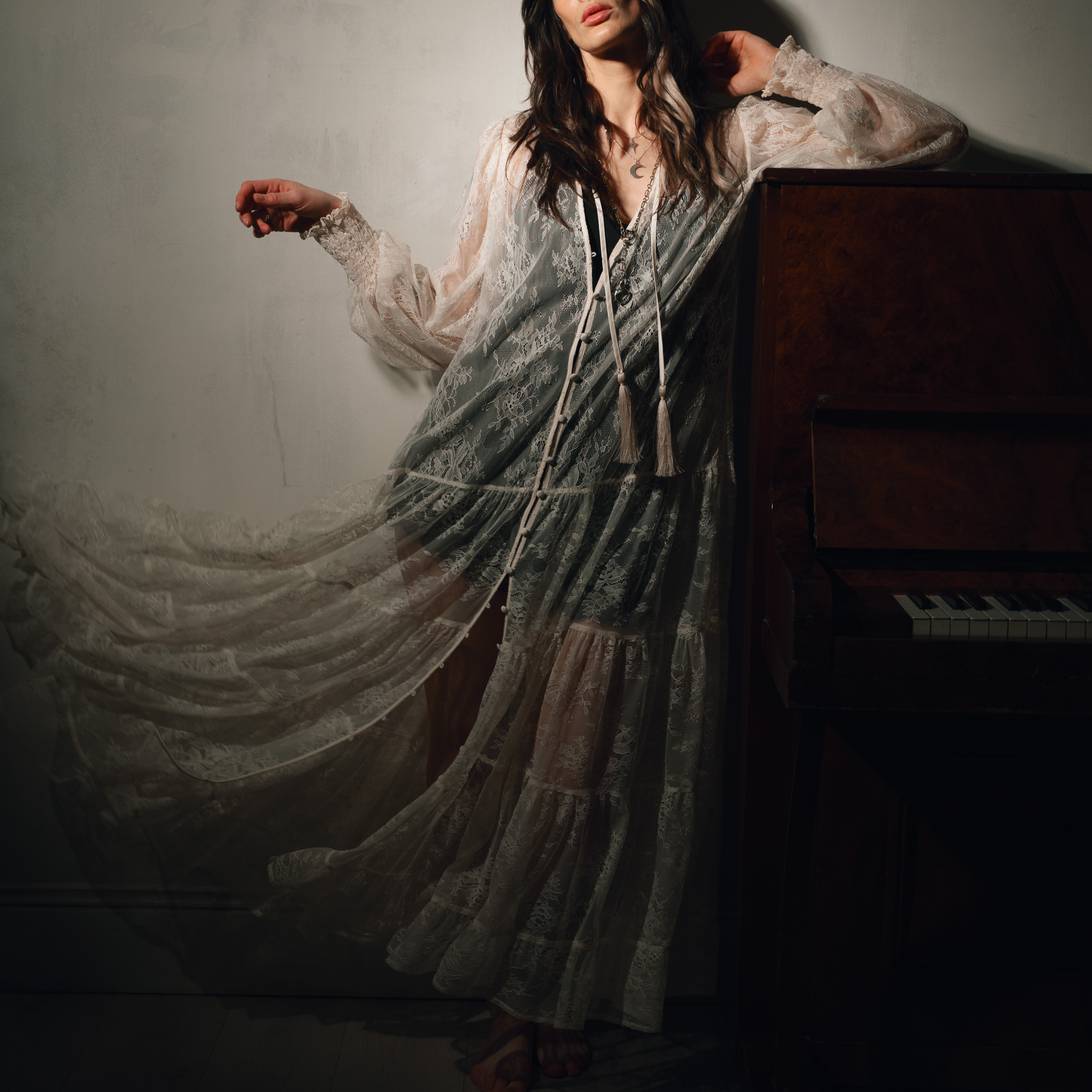 Model Victoria leaning on a piano wearing the Rhiannon Ivory Lace Maxi Dress, A look into the inspiration and making of our first collection of the year, Songbird.