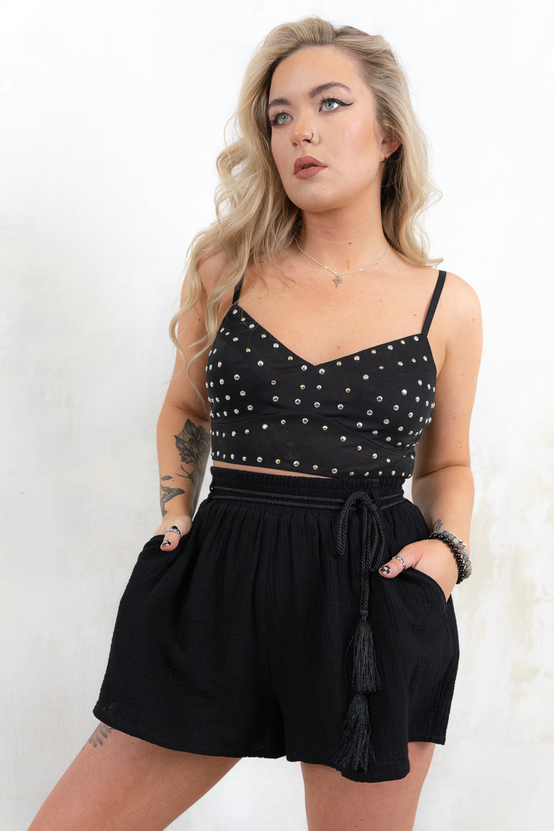 Model wearing Metal Guru Studded Bralette- Black cropped bralette with gold/silver mixed metal studs and adjustable straps and
