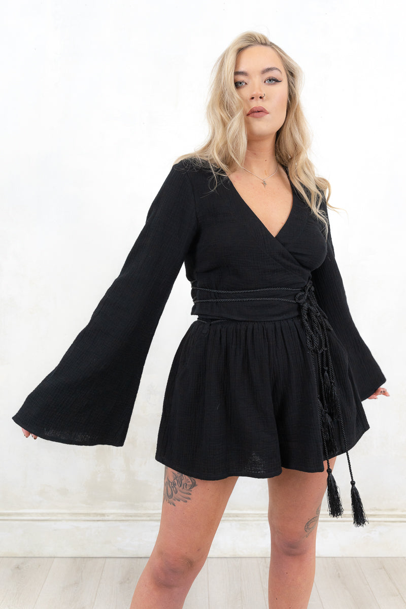 Model wearing Woodstock Flippy Shorts- Black double cheesecloth fabric shorts with high waisted silhouette and elasticated shirred waistband and tassel tie detail