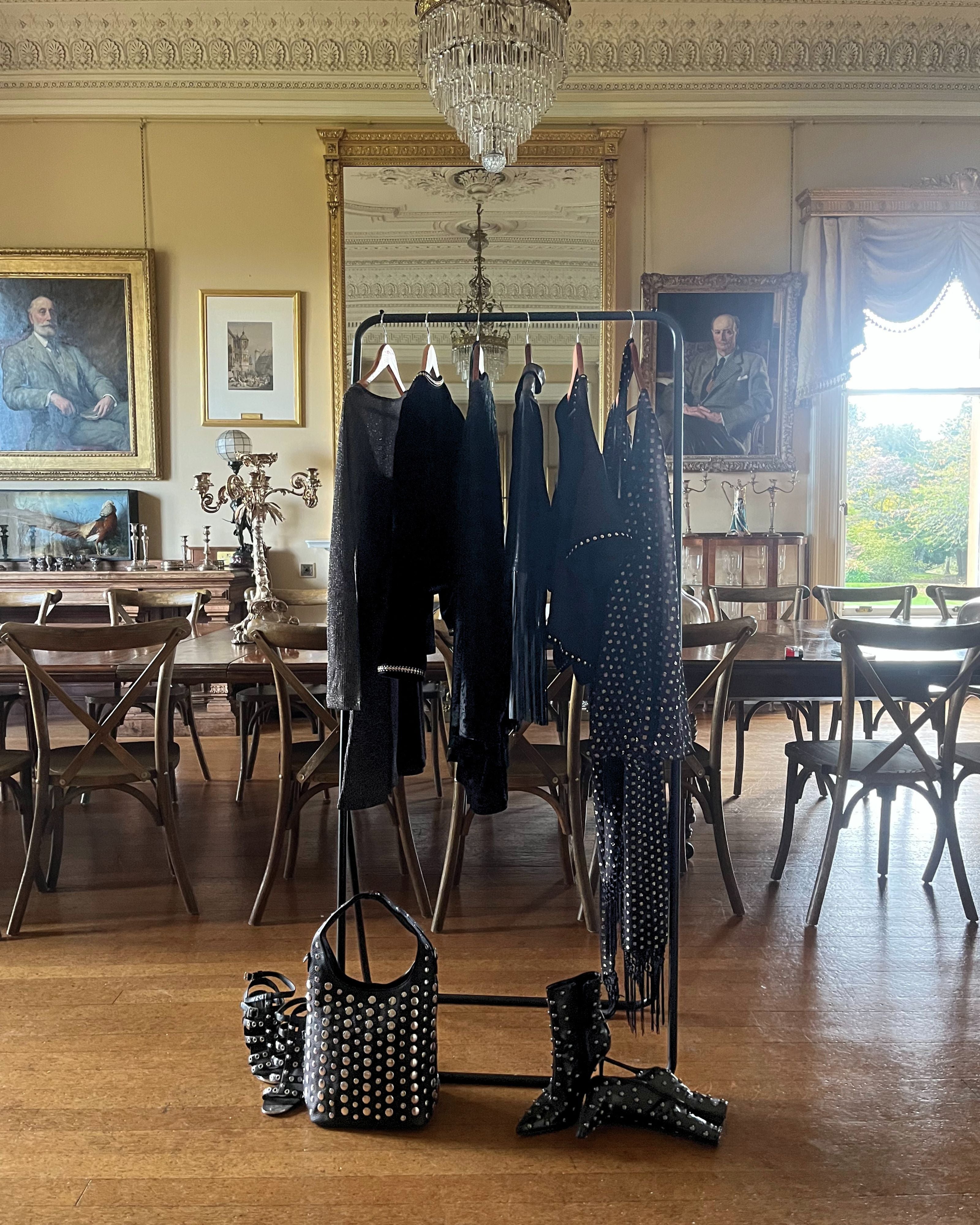 Clothing rail filled with the Party Collection including black velvets, metallic shimmer wrap and mini dresses, studded top and fringed leather jackets. 