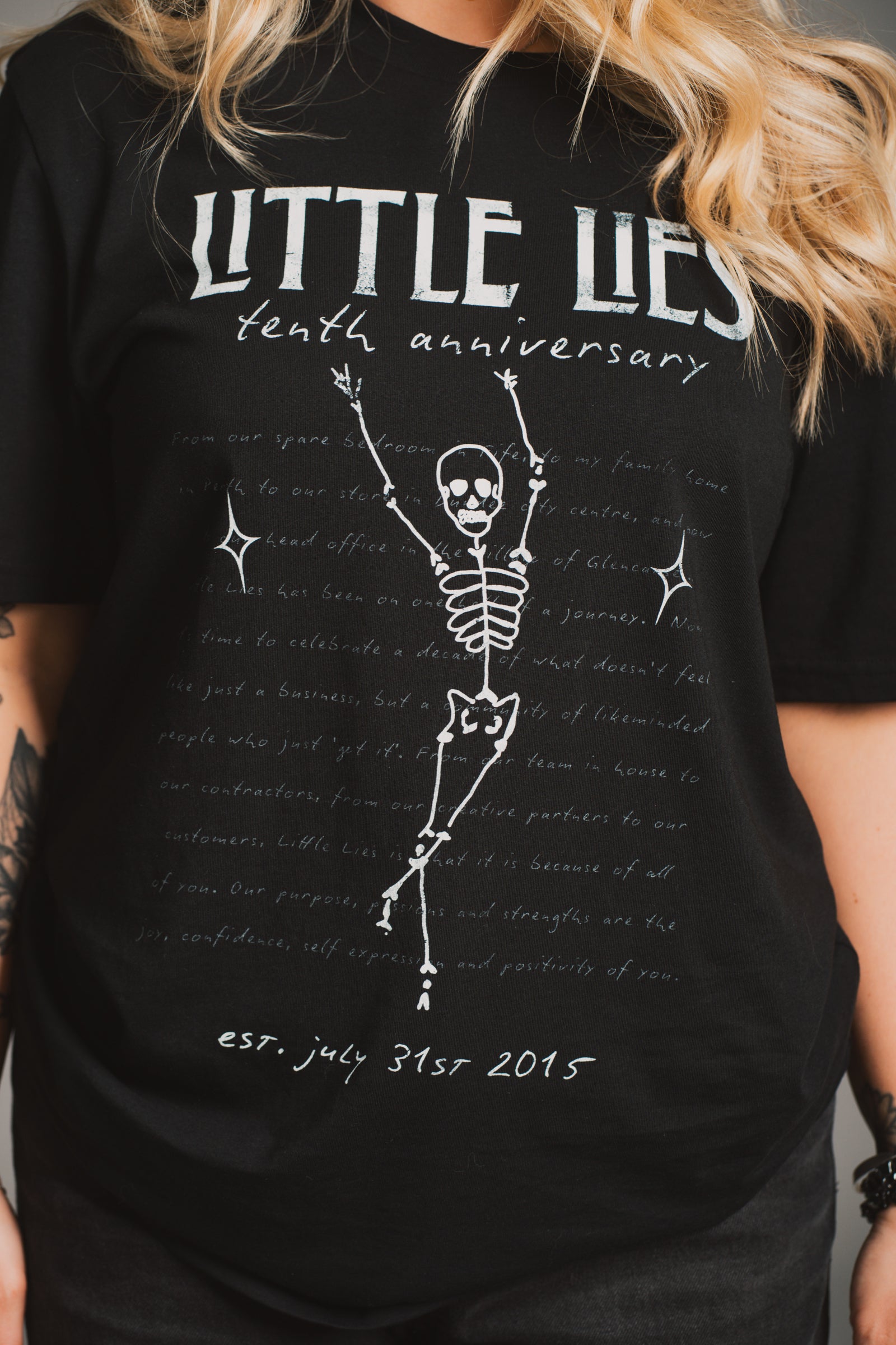 Model wearing Little Lies 10th Anniversary Graphic black t-shirt with vintage Little Lies design.