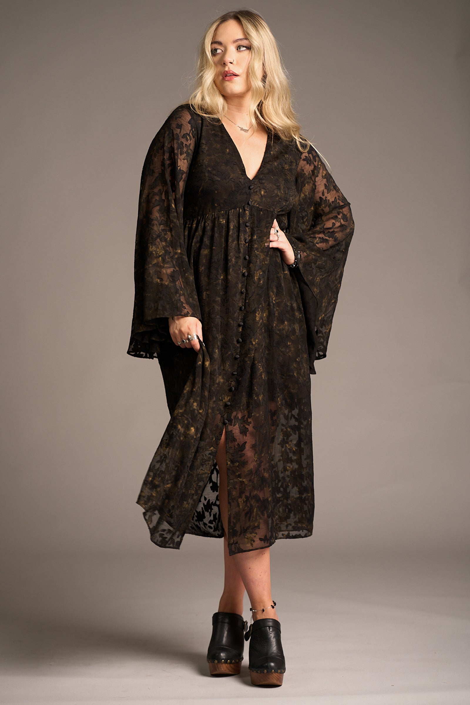 Erin wears the Bella Donna Midi Dress featuring sheer black floral overlay and bell sleeves against a neutral backdrop, Stevie Nicks inspired styling studio