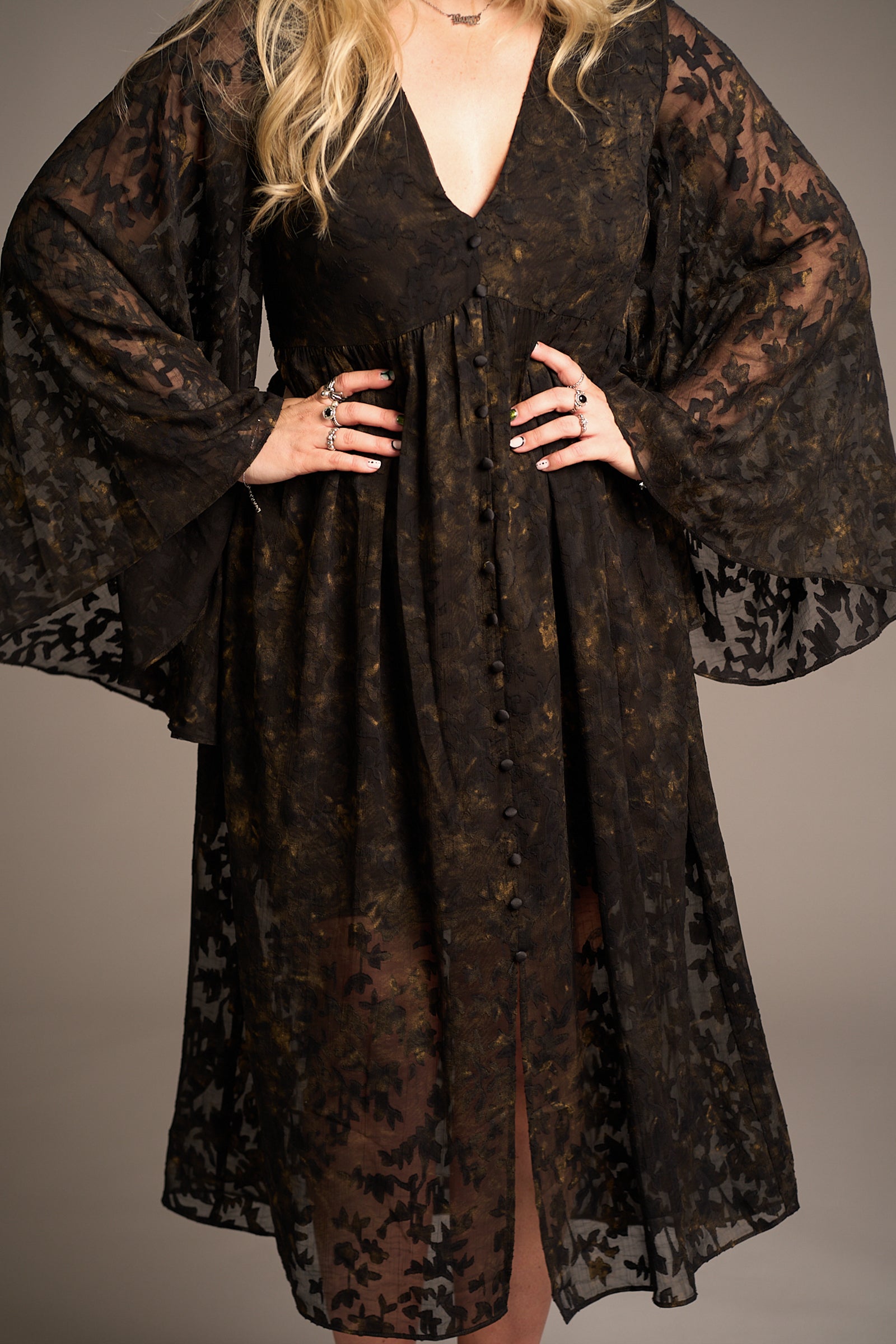 Close-up of Bella Donna Midi Dress worn by Erin, featuring floral lace, wide sleeves, and statement rings against a neutral background