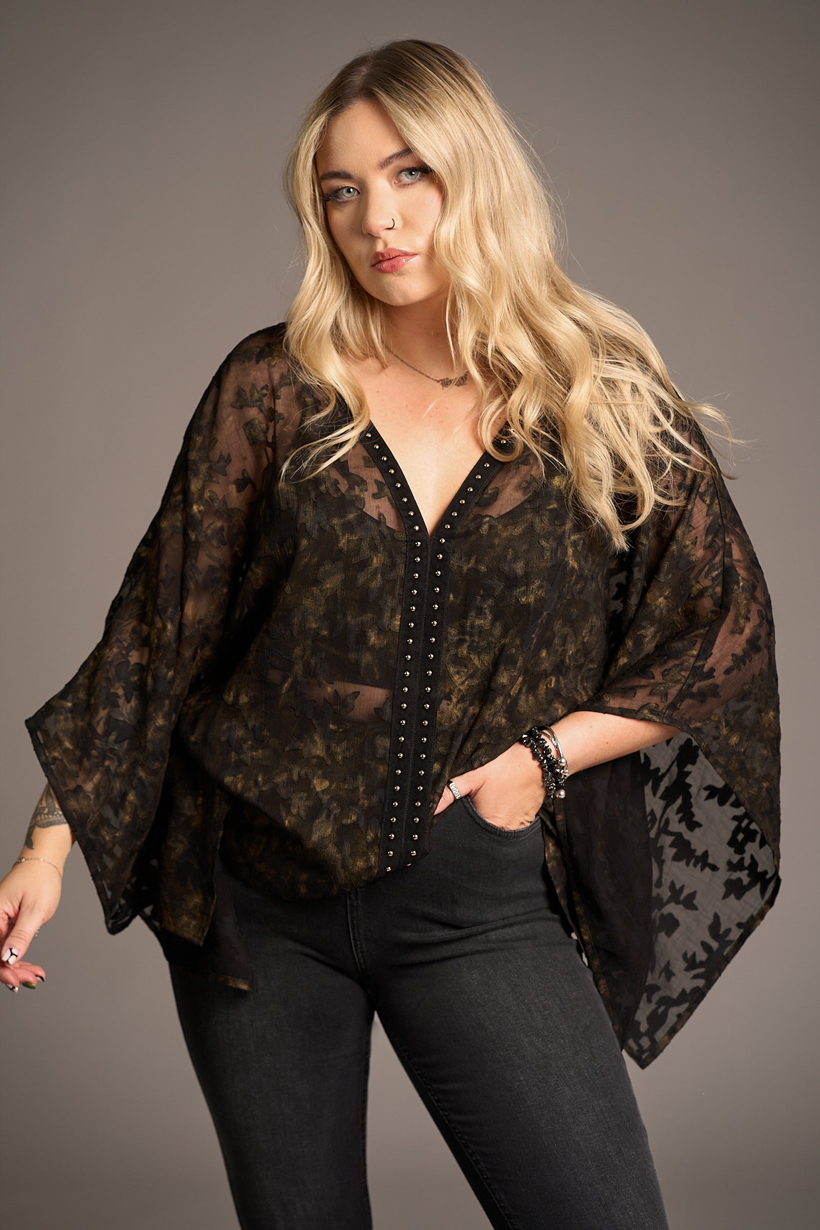 Erin in Bella Donna Studded Kimono Top
with studded accents, and flared jeans, against a neutral backdrop, Stevie Nicks inspired styling studio