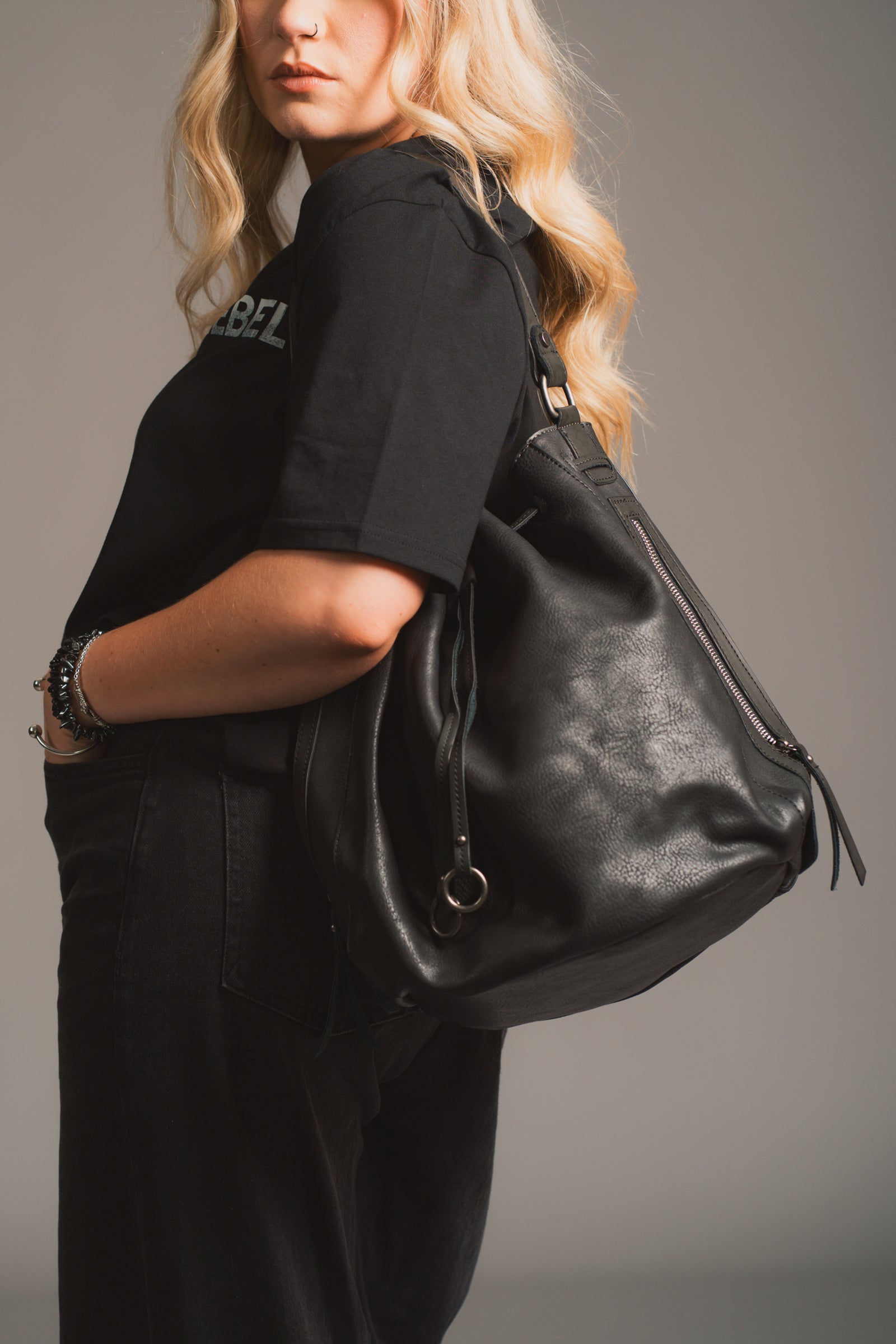 Model holding the Dakota Black Hobo Bag in front of a black background. 