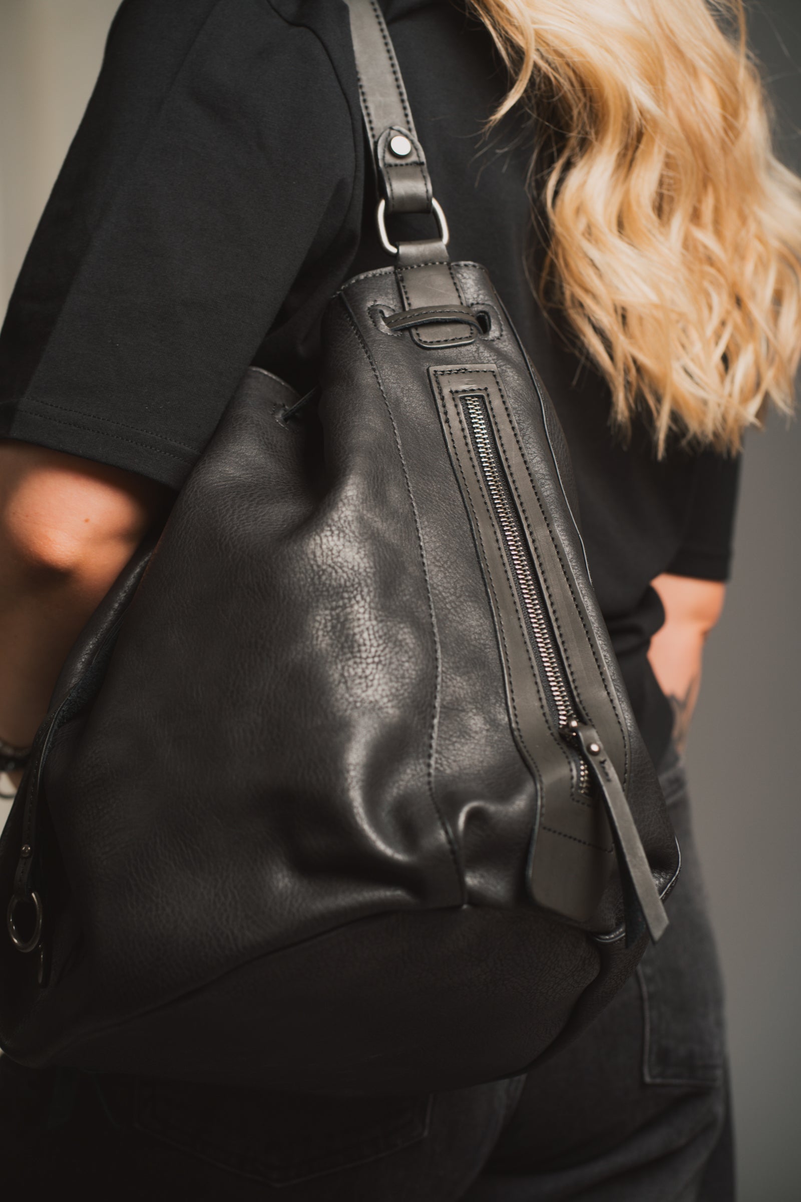 Model holding the Dakota Black Hobo Bag in front of a black background. 