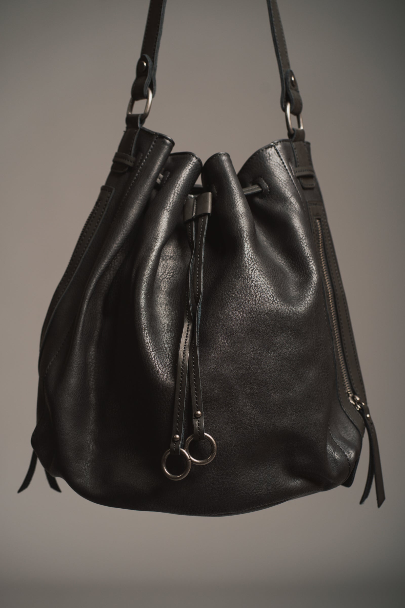 Model holding the Dakota Black Hobo Bag in front of a black background. 