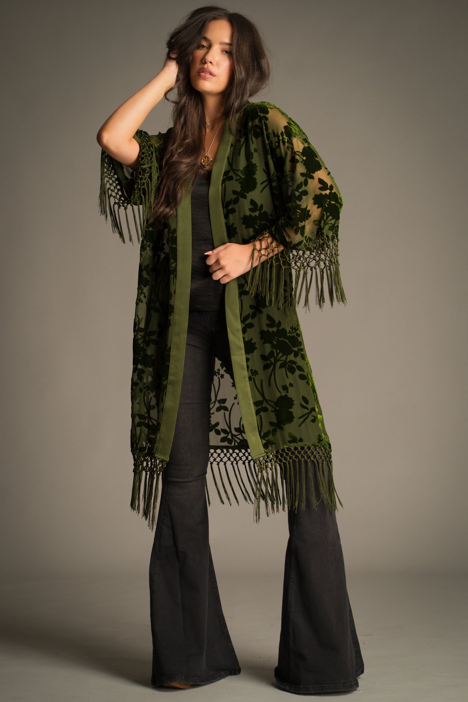 Model wearing Little Lies Dakota olive devore kimono styled with black cami and denim flares – lightweight sheer layering piece with velvet floral detail and tassel trim