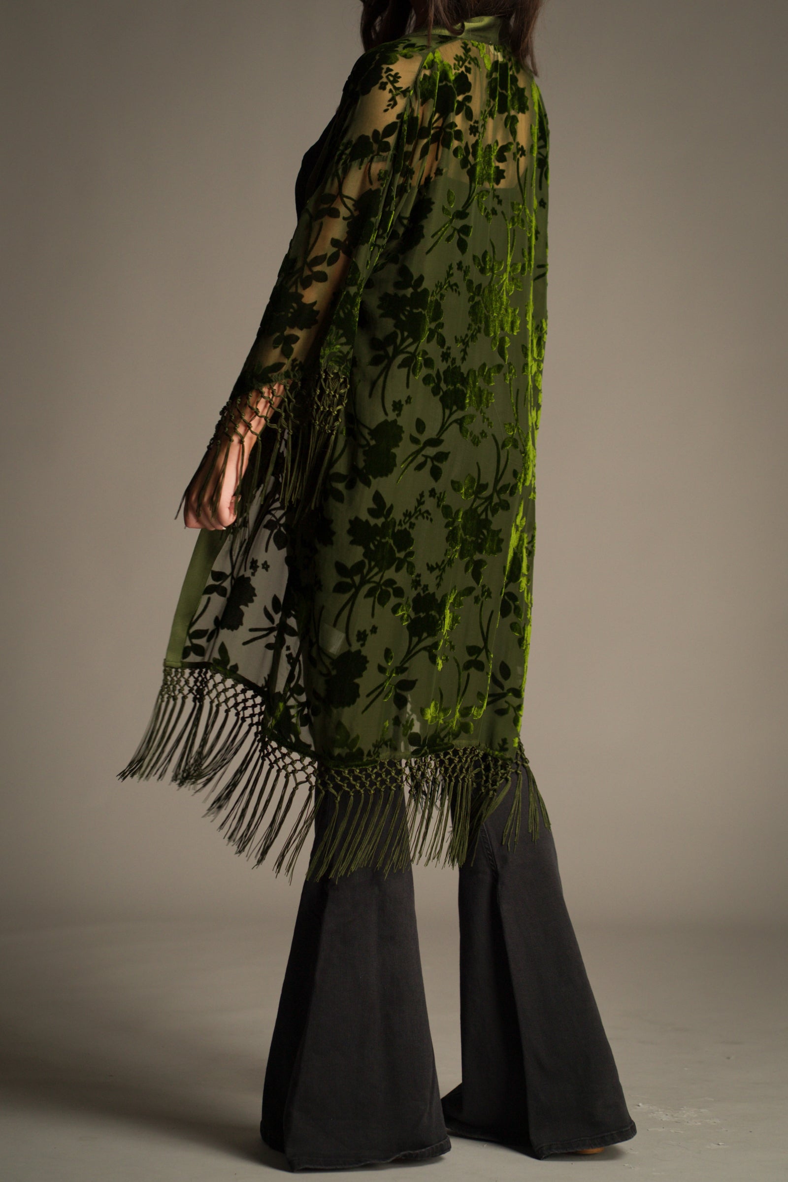 Side view of Little Lies Dakota olive devore kimono with sheer fabric, velvet floral pattern and flowing silhouette with tassel fringe