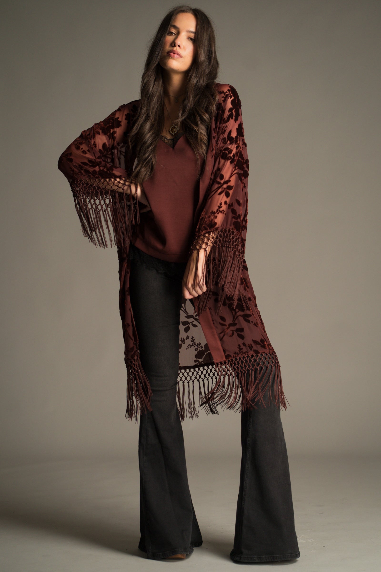 Front view of the Dakota Rust Floral Devore Kimono in sheer rust devoré with tassel fringe hem. Styled with Hendrix Denim Flares.