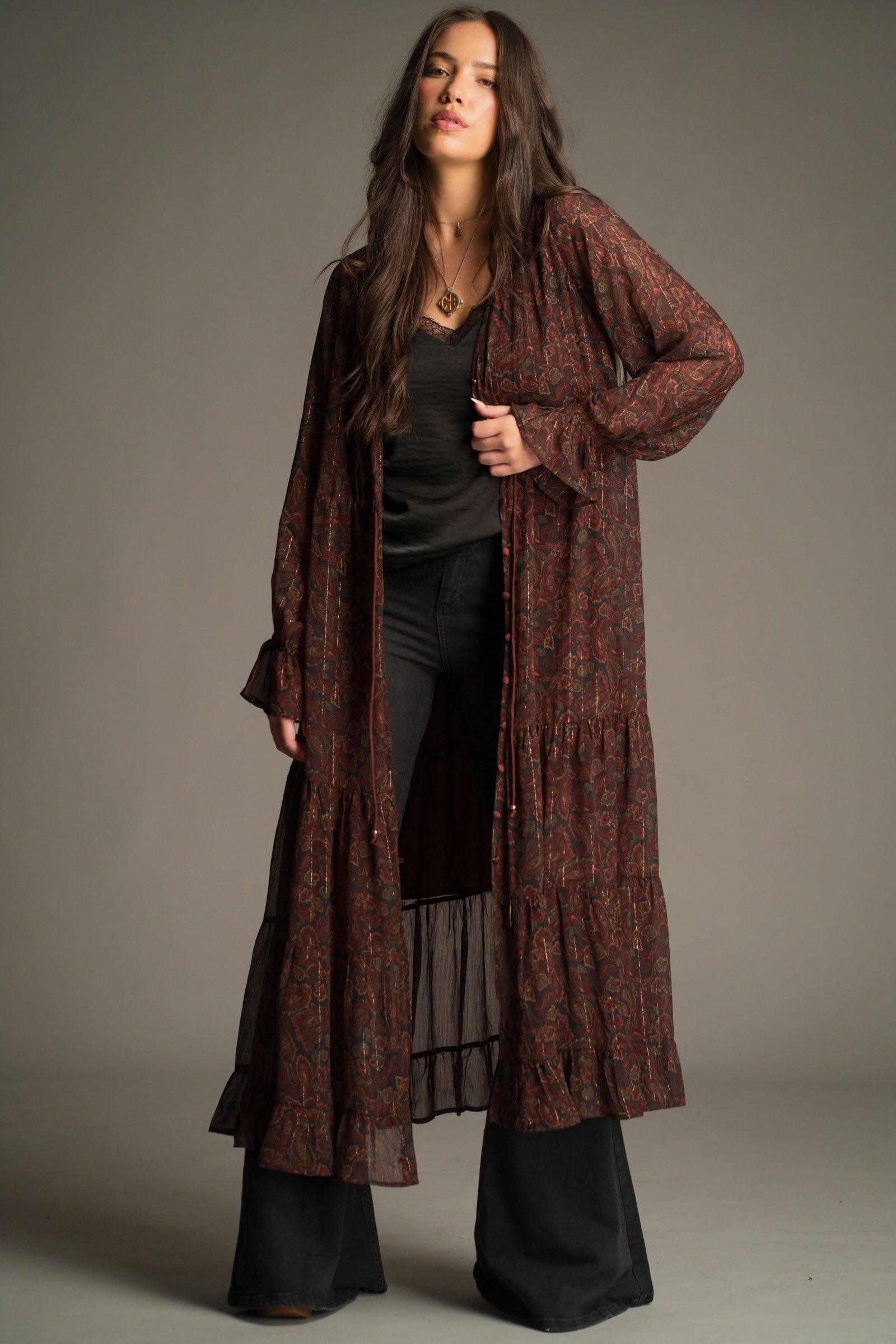 Dark Paradise Paisley Maxi Dress worn open as a kimono showing drawstring waist and gold bead ties. Styled with Hendrix Denim Flares.