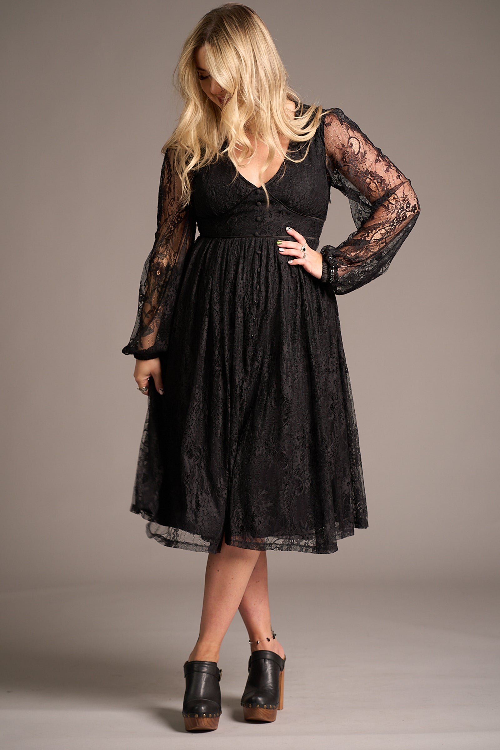 Erin wears the Dazed Black Lace Midi Dress with sheer sleeves and V-neckline, styled with platform shoes – studio shoot highlighting elegant lace detail and flattering A-line fit.