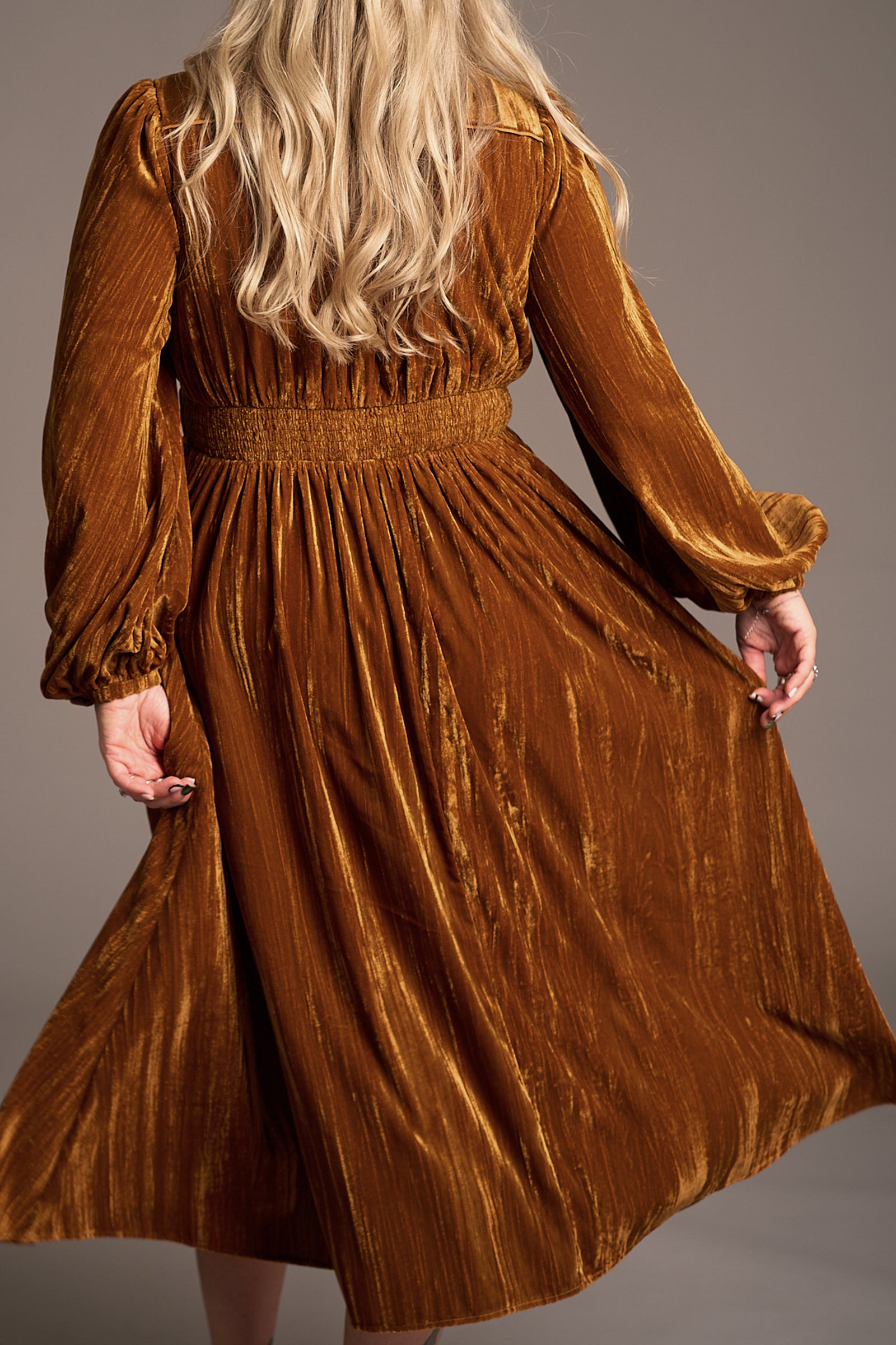 Back view of Erin in Dazed Copper Velvet Midi Dress with flowing silhouette, ruched waist and voluminous sleeves