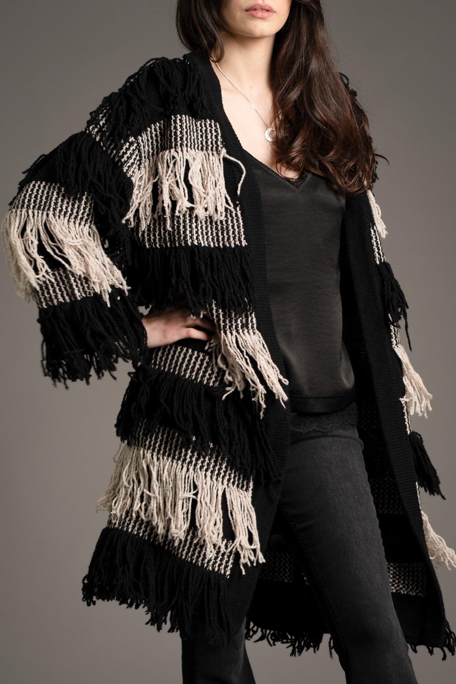 Close-up of Little Lies Desperado Shaggy Cardigan in black and cream fringe knit, styled with Nightbird Lace Trim Cami Top and Hendrix Denim flared jeans, studio setting