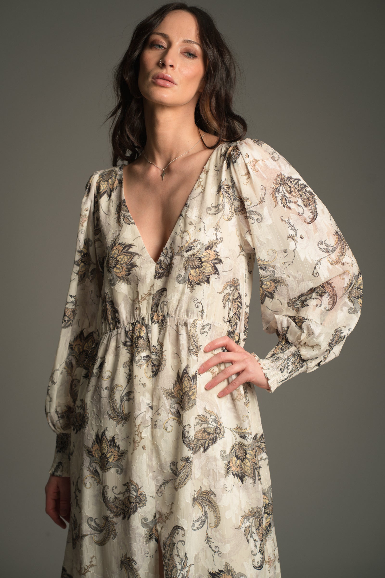 Victoria wears Little Lies Harvest Moon Paisley Midi Dress in cream with detailed paisley print, close‑up front view showing deep V‑neckline and long balloon sleeves with shirred cuffs.