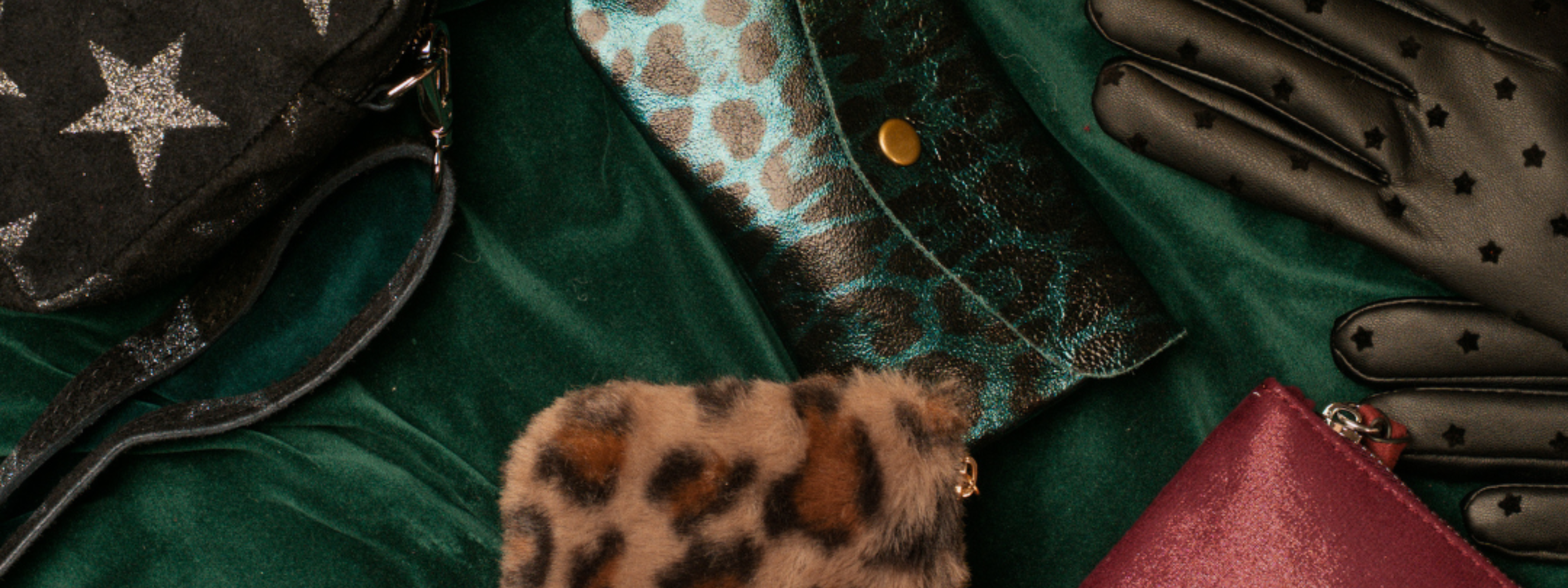 Little Lies gift shop header featuring Radar Love star print crossbody bag, Leopard Faux Fur pouch, Burgundy Star Pouch, Teal Metallic Genuine Suede snakeskin purse, and Black Star Faux Leather Gloves on green velvet backdrop