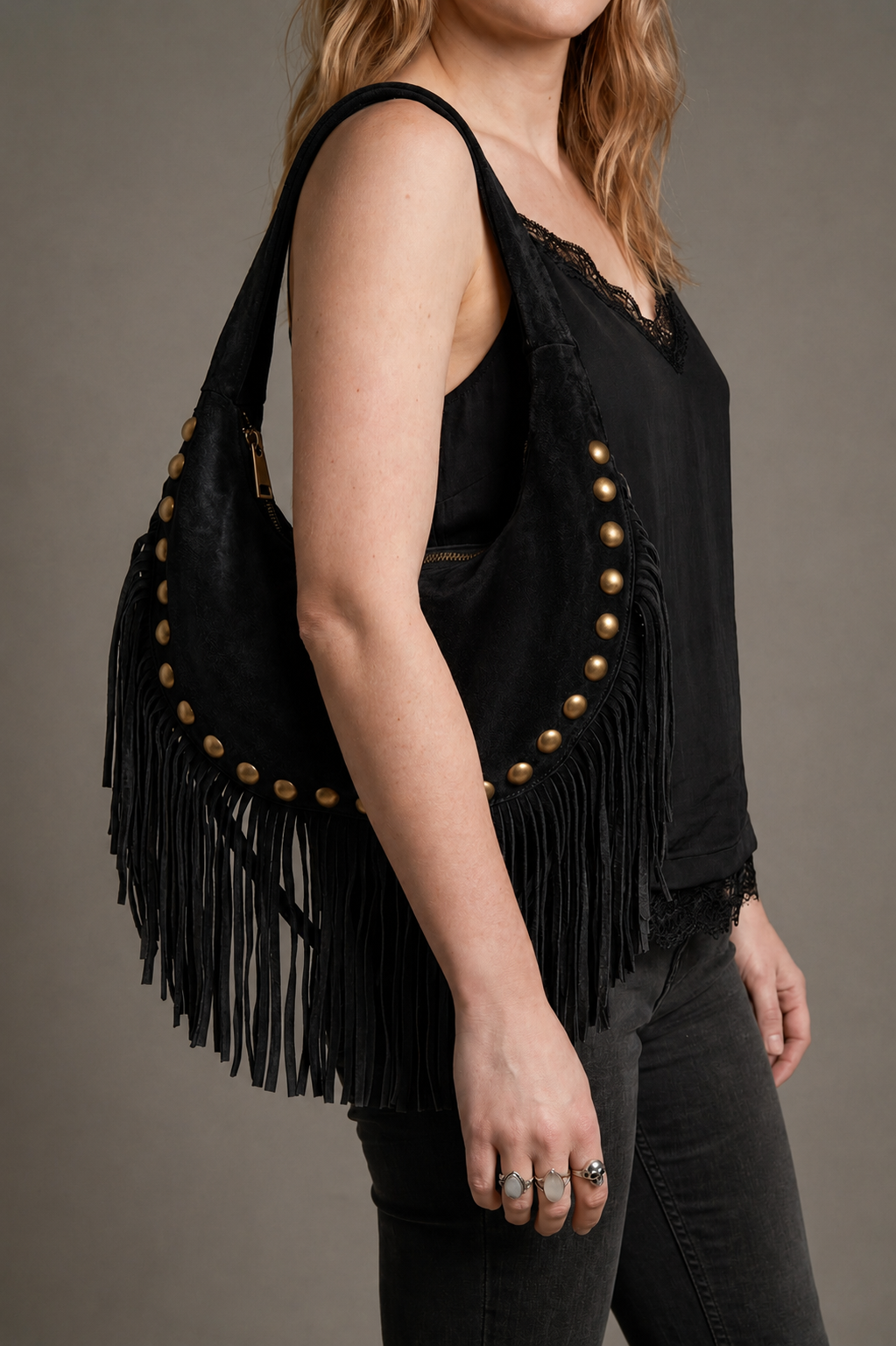 Little Lies Kate black genuine suede studded fringe bag, slouchy hobo style with tassel trim, on‑body side view