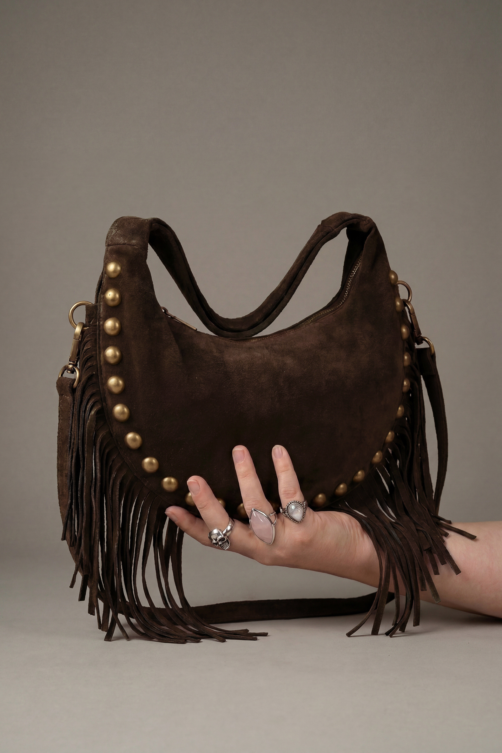 Little Lies Kate chocolate suede studded fringe bag – relaxed shoulder bag front held by model