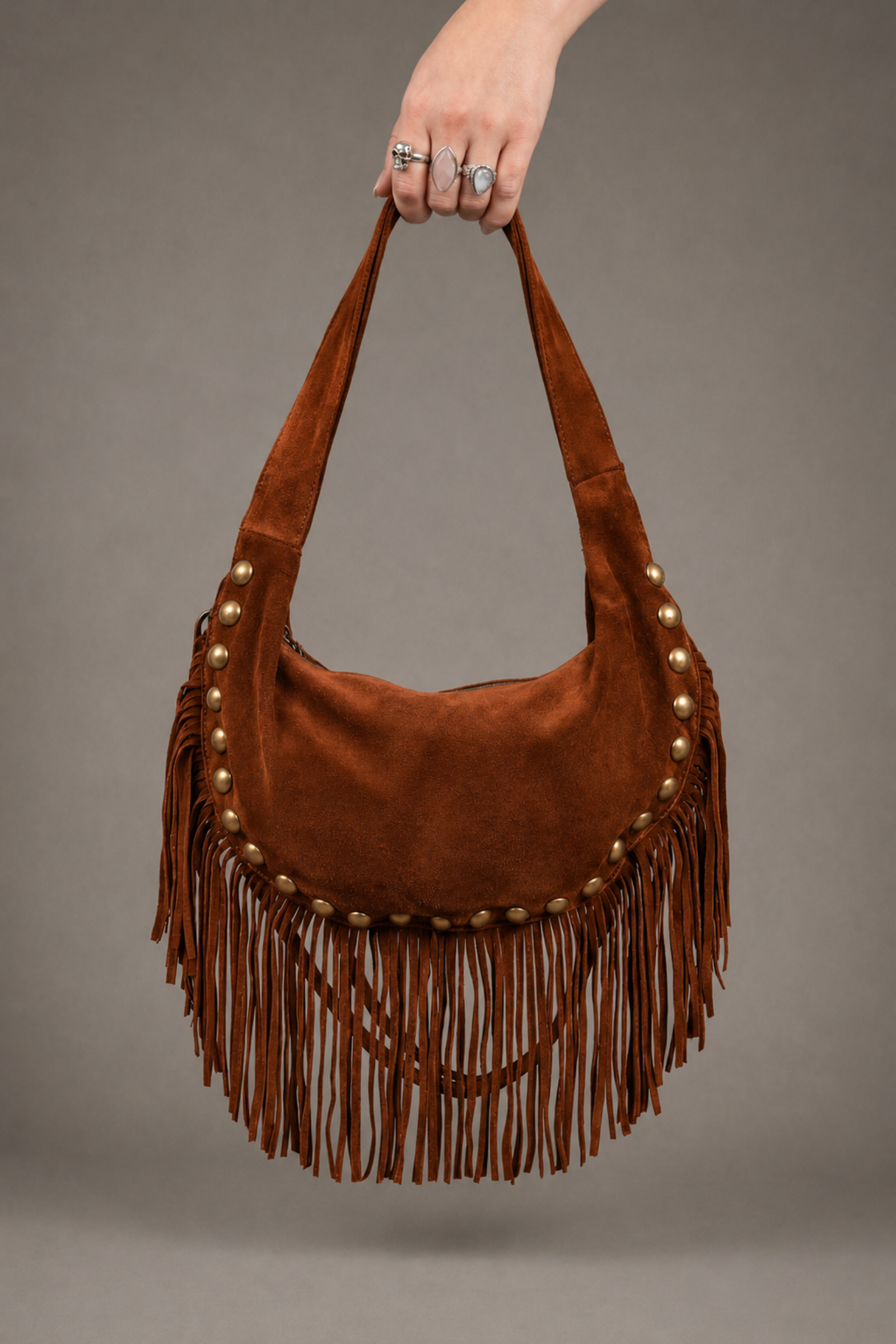 Little Lies Kate tan suede studded fringe bag – relaxed shoulder bag front held by model