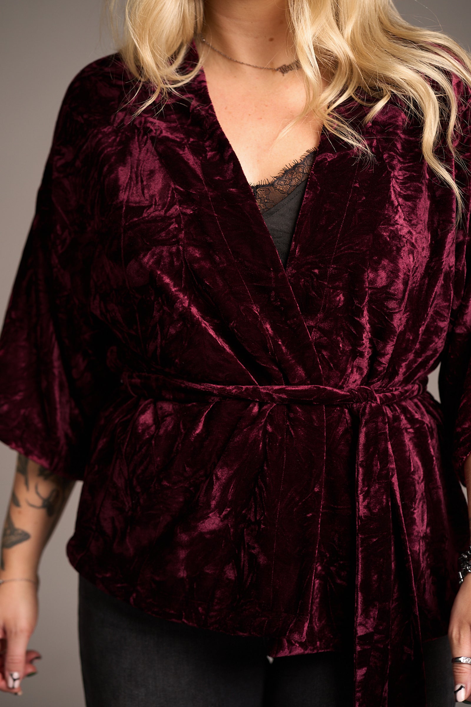 Close up of Erin showcasing the Lana Merlot Velvet Kimono in rich burgundy velvet with wrap front and wide sleeves over black lace top