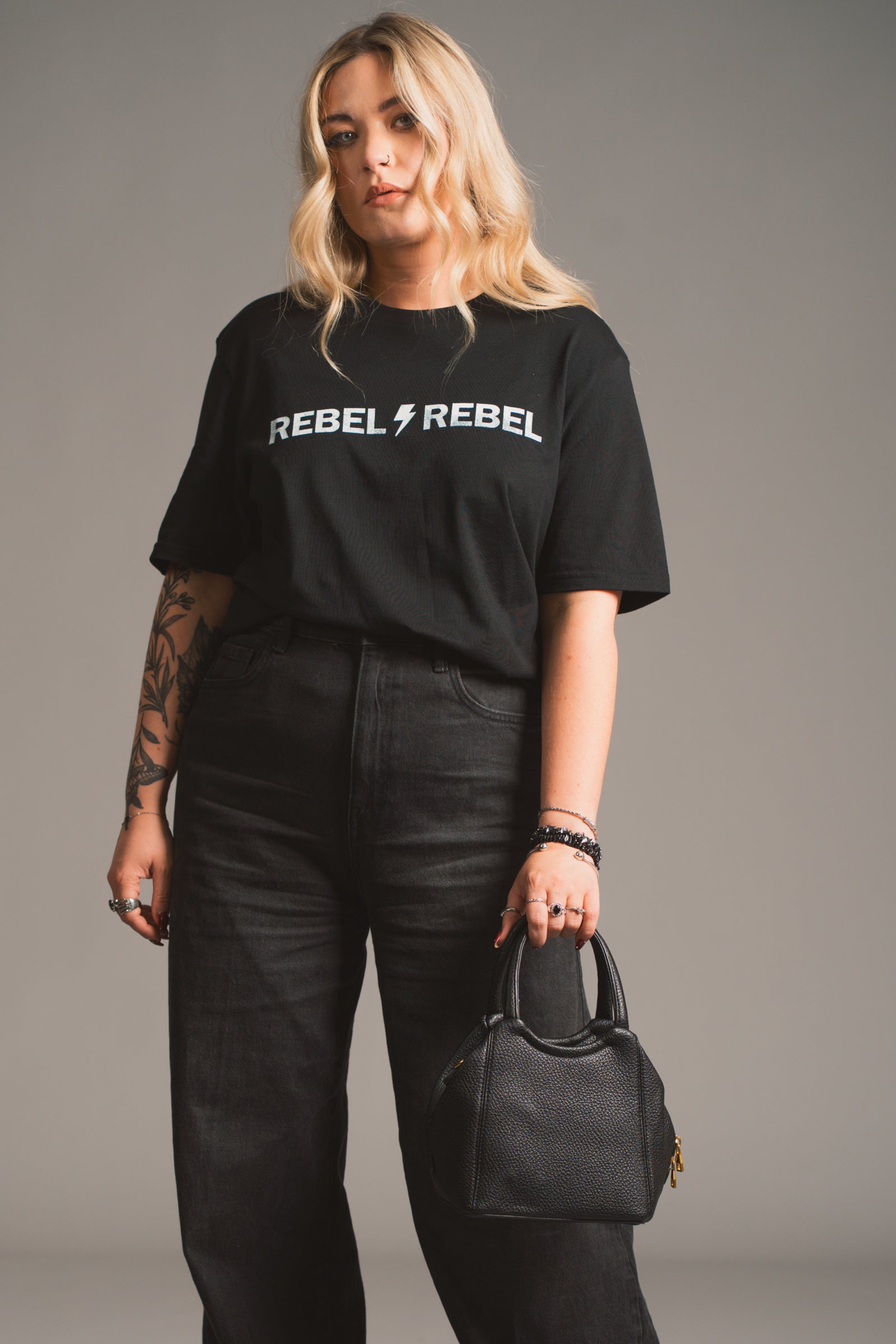 Model holding the Lana Faux Leather Black Mini Bag against styles with Rebel Rebel Tee