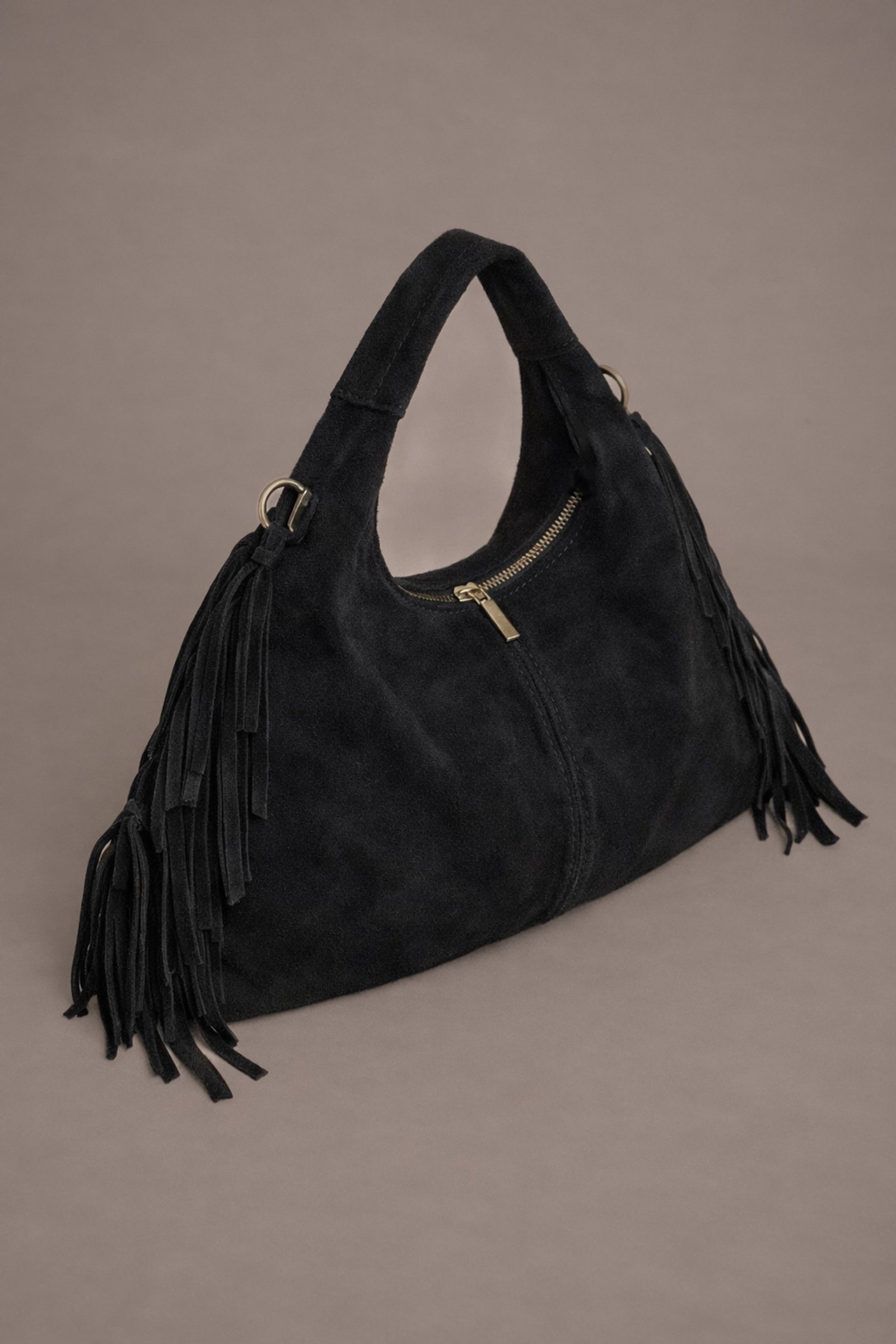 Little Lies Lila black genuine suede fringed grab bag with gold hardware and zip detail in studio setting.