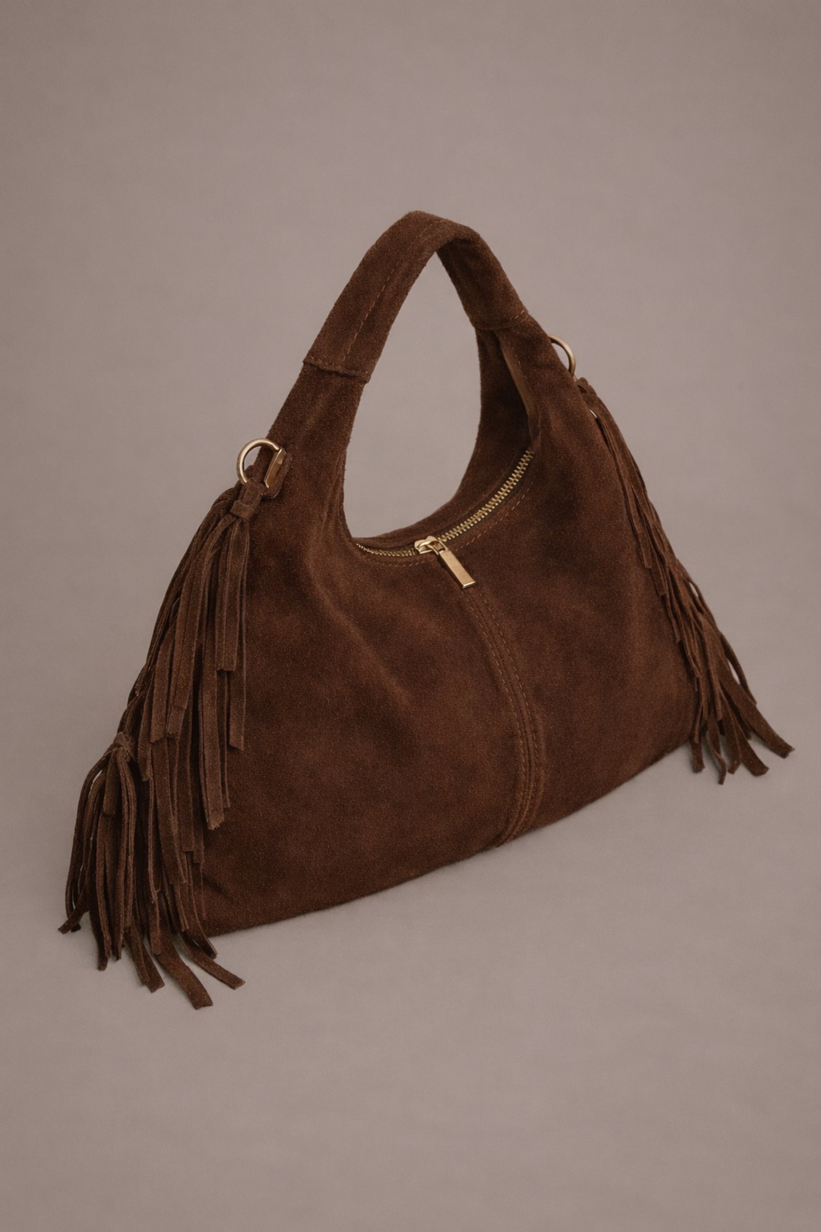 Little Lies Lila chocolate genuine suede fringed grab bag with gold metal hardware and zip detail in studio setting.