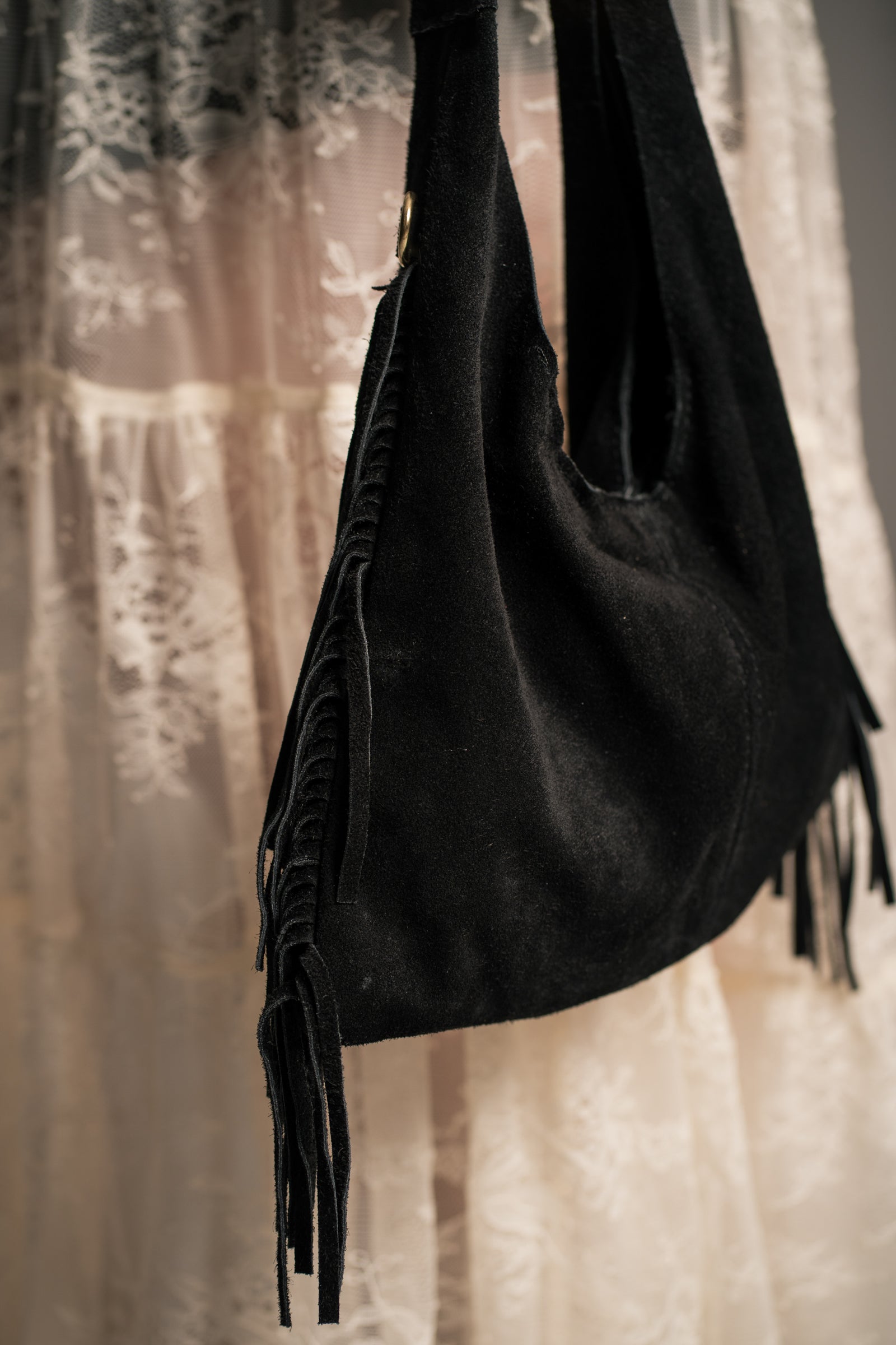 Little Lies Lila black genuine suede fringed grab bag, soft hobo style with tassel fringe, on‑body detail view