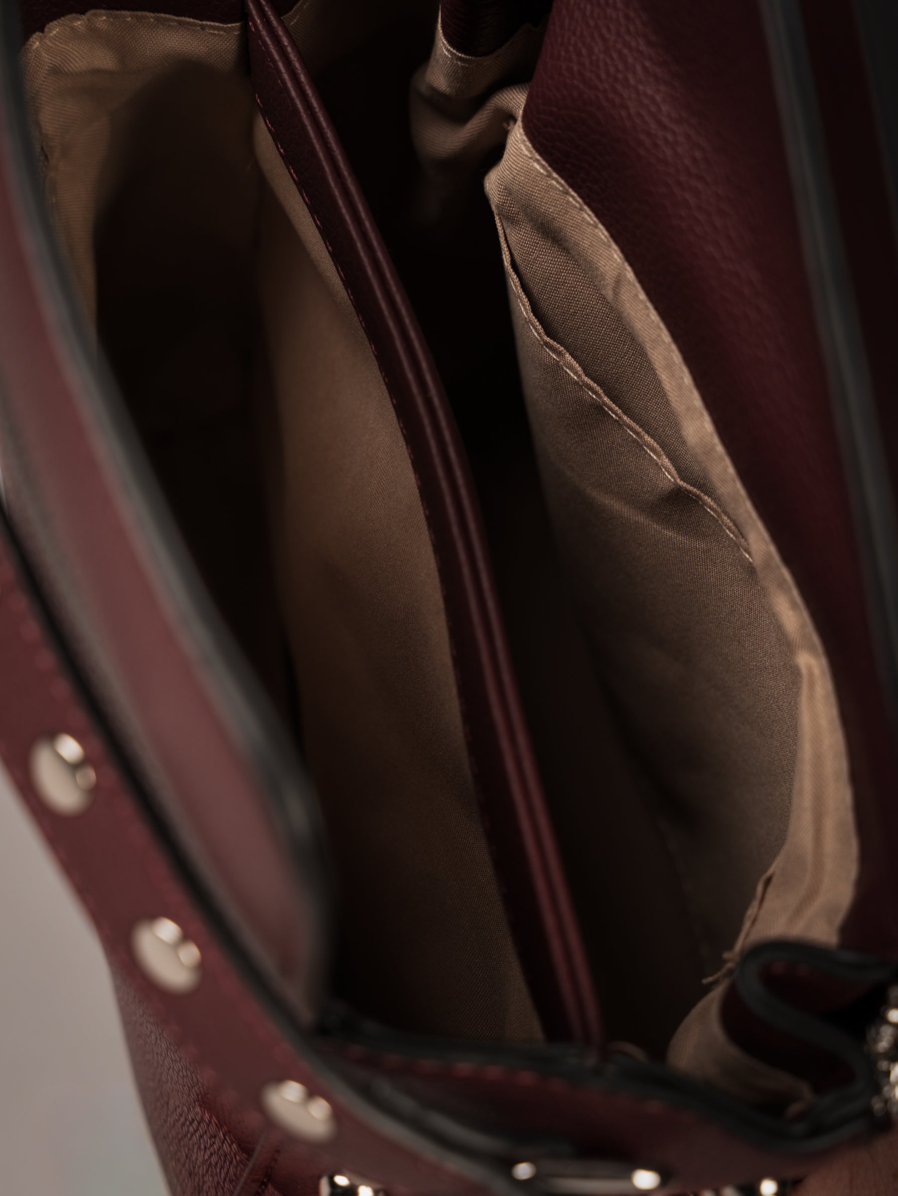 Little Lies Leo Burgundy studded box bag interior view showing beige lining and compartments