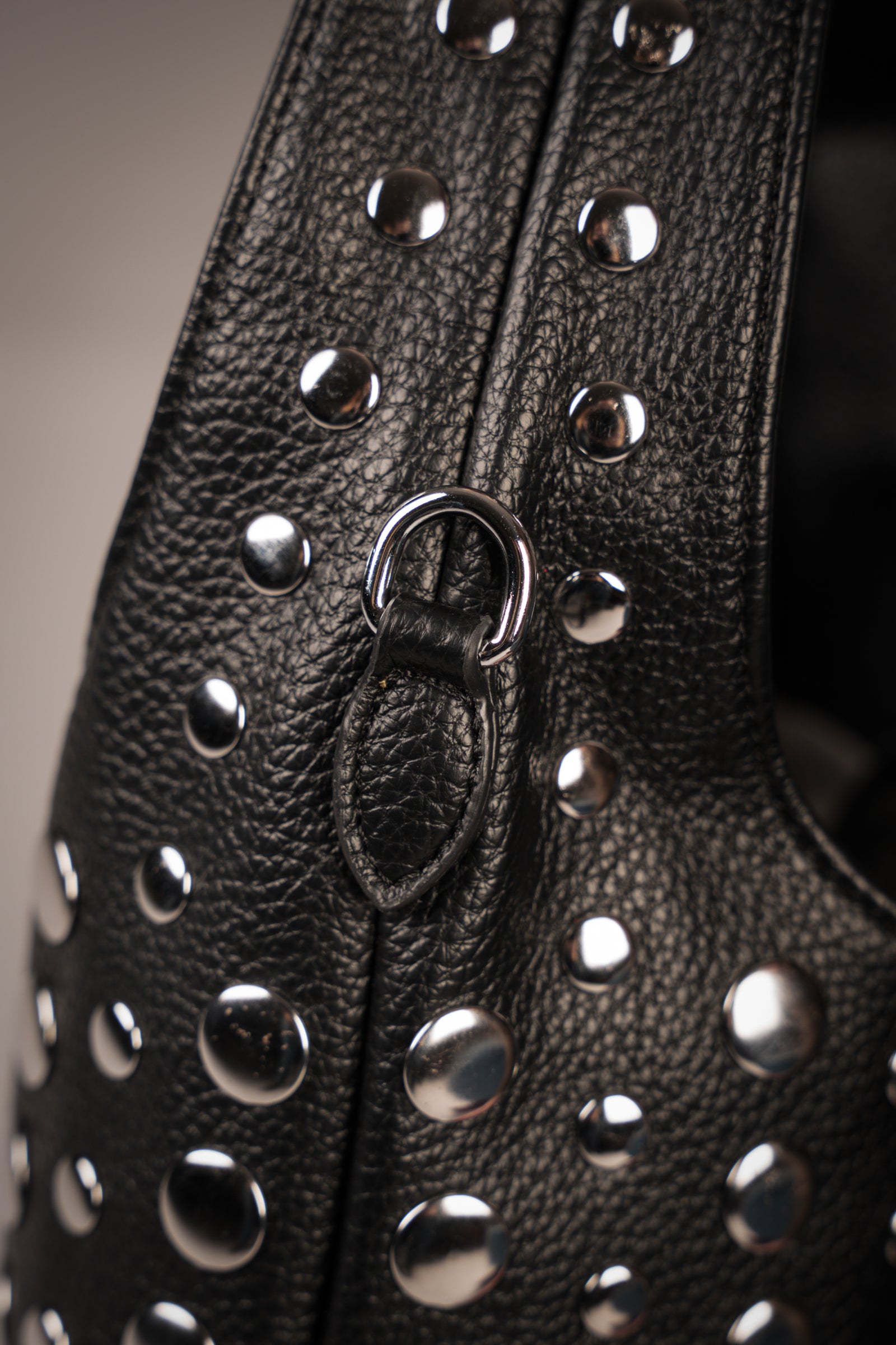 Close-up of Little Lies Viva black leather handbag featuring silver-tone stud hardware and textured finish, studio setting