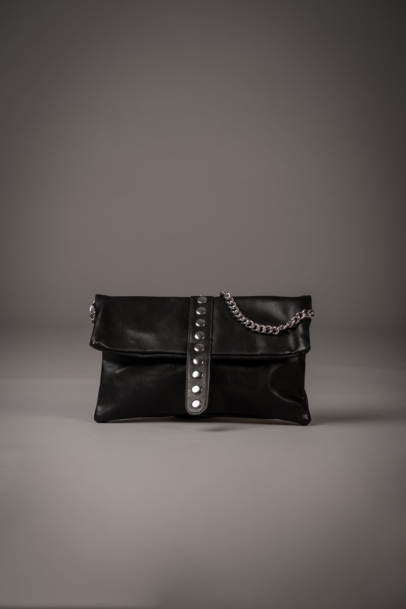 Little Lies Zoë studded black faux leather clutch with silver-tone studs and chain detail, photographed in a studio setting
