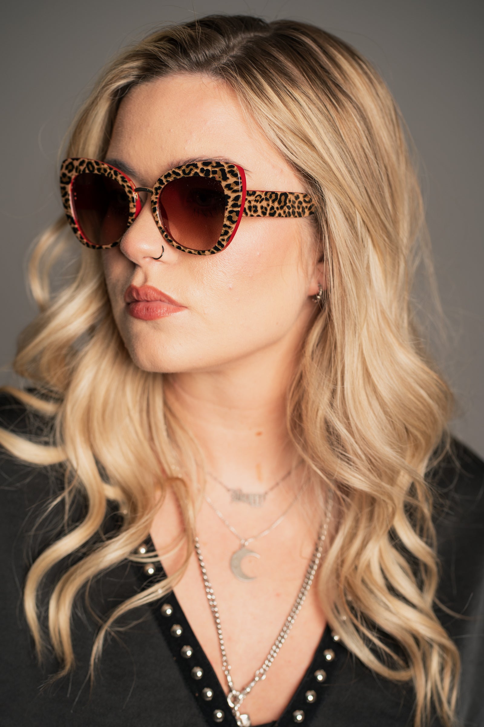Little Lies Lola retro leopard print sunglasses with red frame detail and brown tinted lenses, oversized statement style, on‑model close‑up view